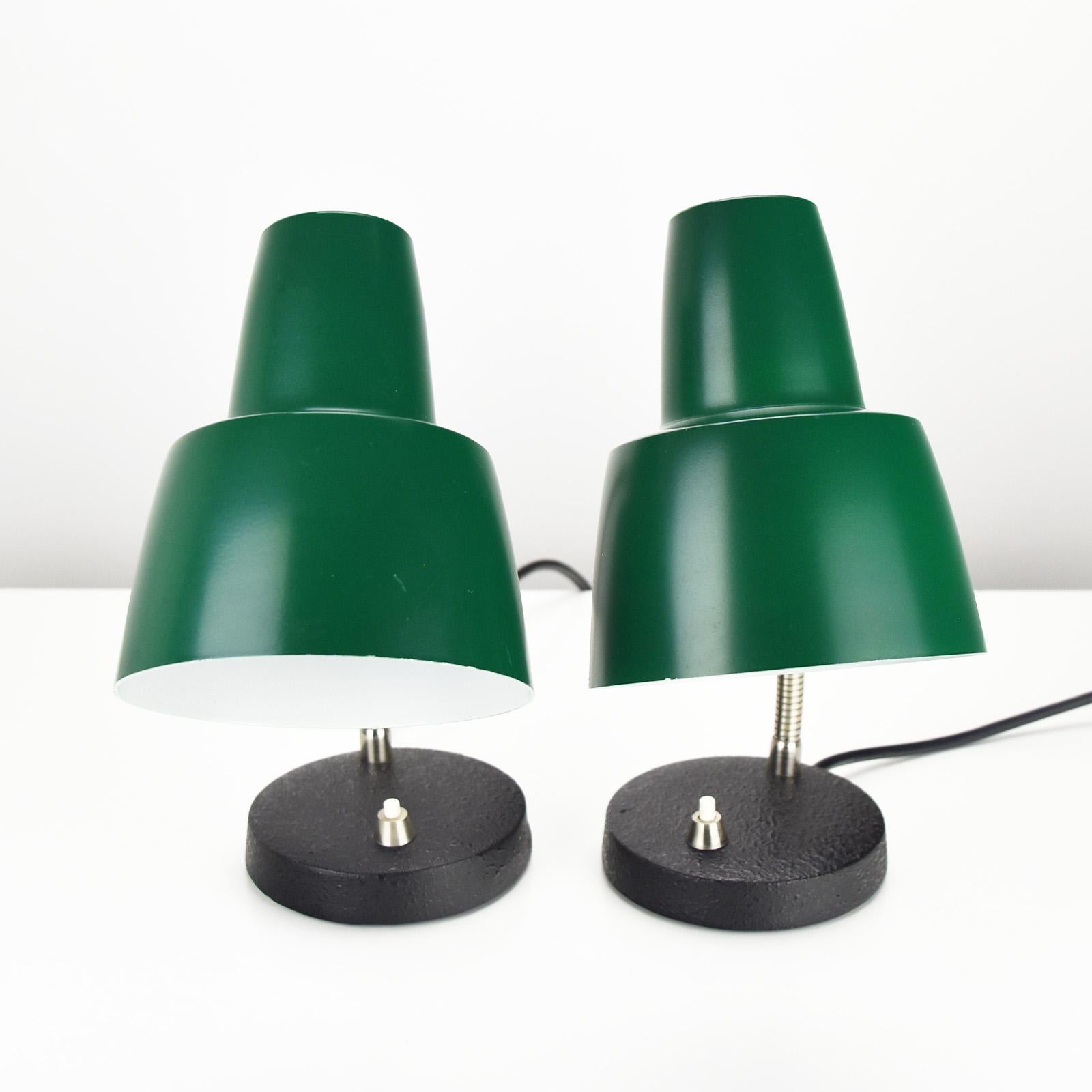 Nice pair of bed side table lamp by the German manufacturer Hillebrand dating to the 1960s. 
The lamps are in pristine condition, cleaned and full in function. 
The base is made of black patinated cast iron, chromed gooseneck and green lacquered