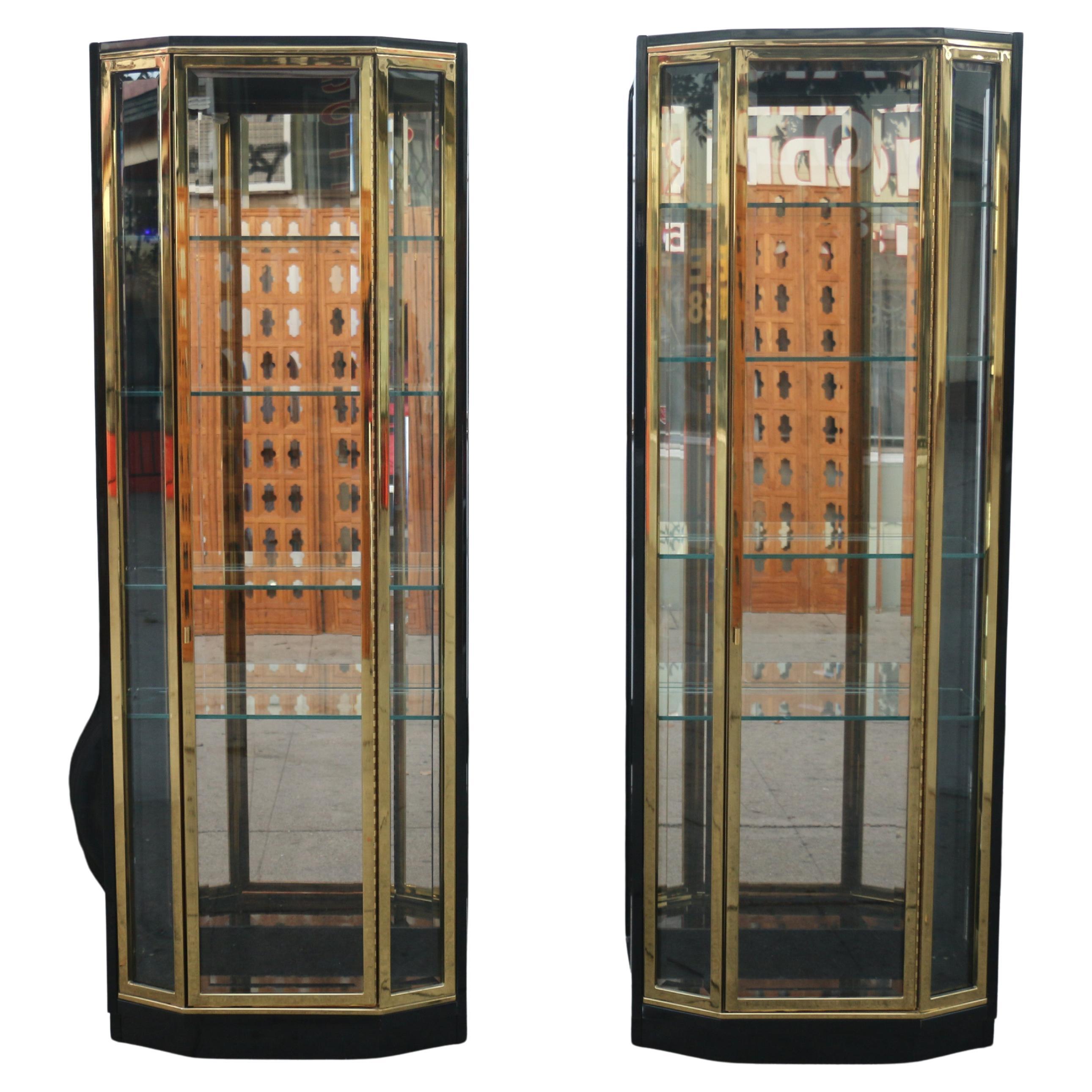 Spectacular pair of tall black lacquer and brass vitrines designed by Henredon, (they have the label in the back). Featuring clean lacquered frames with brass trim on the doors. The cabinets feature beveled glass sides and doors. Both of them have