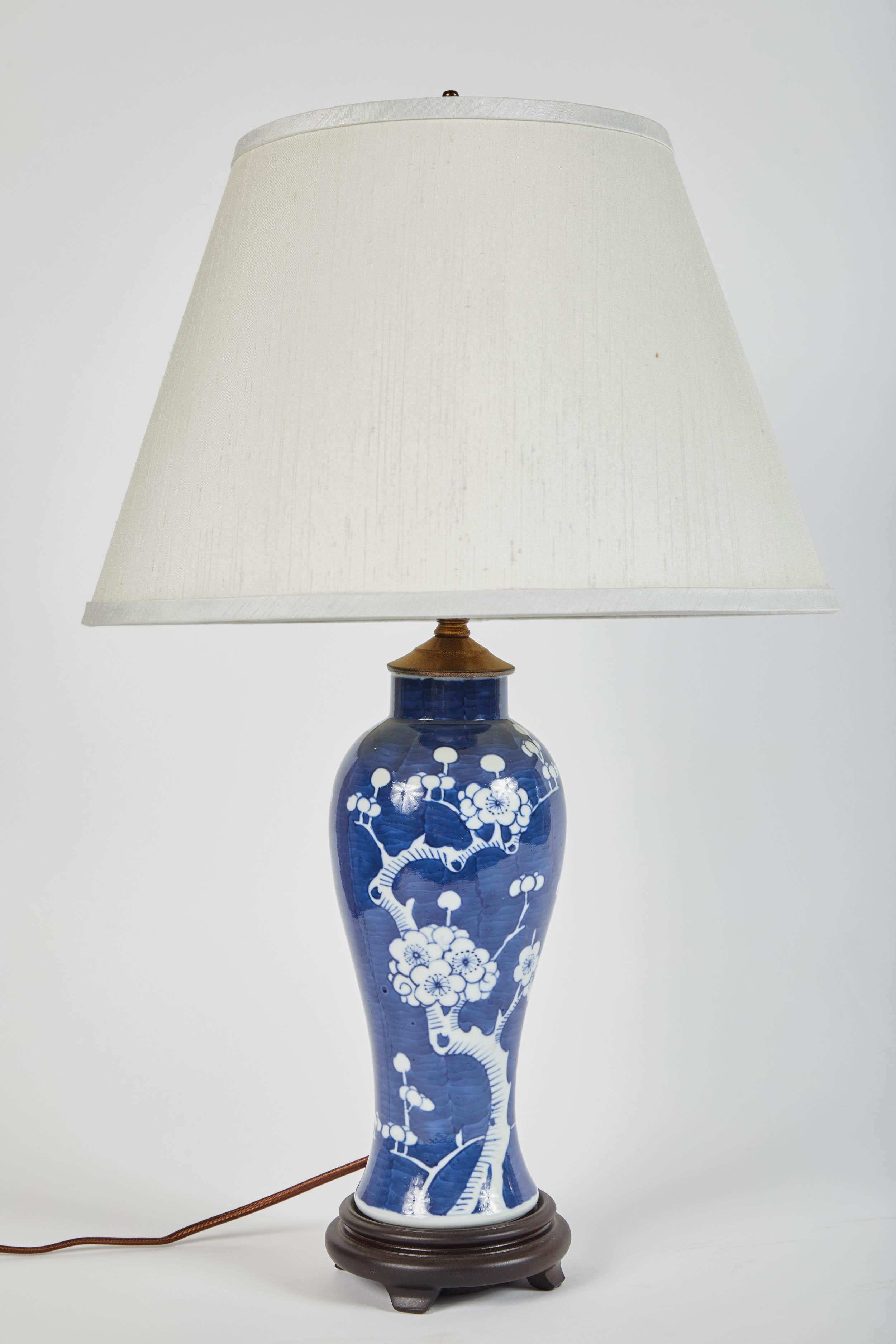 A pair of 20th century blue and white vases featuring cherry blossom motif. Turned into electrified table lamps with ivory shades.