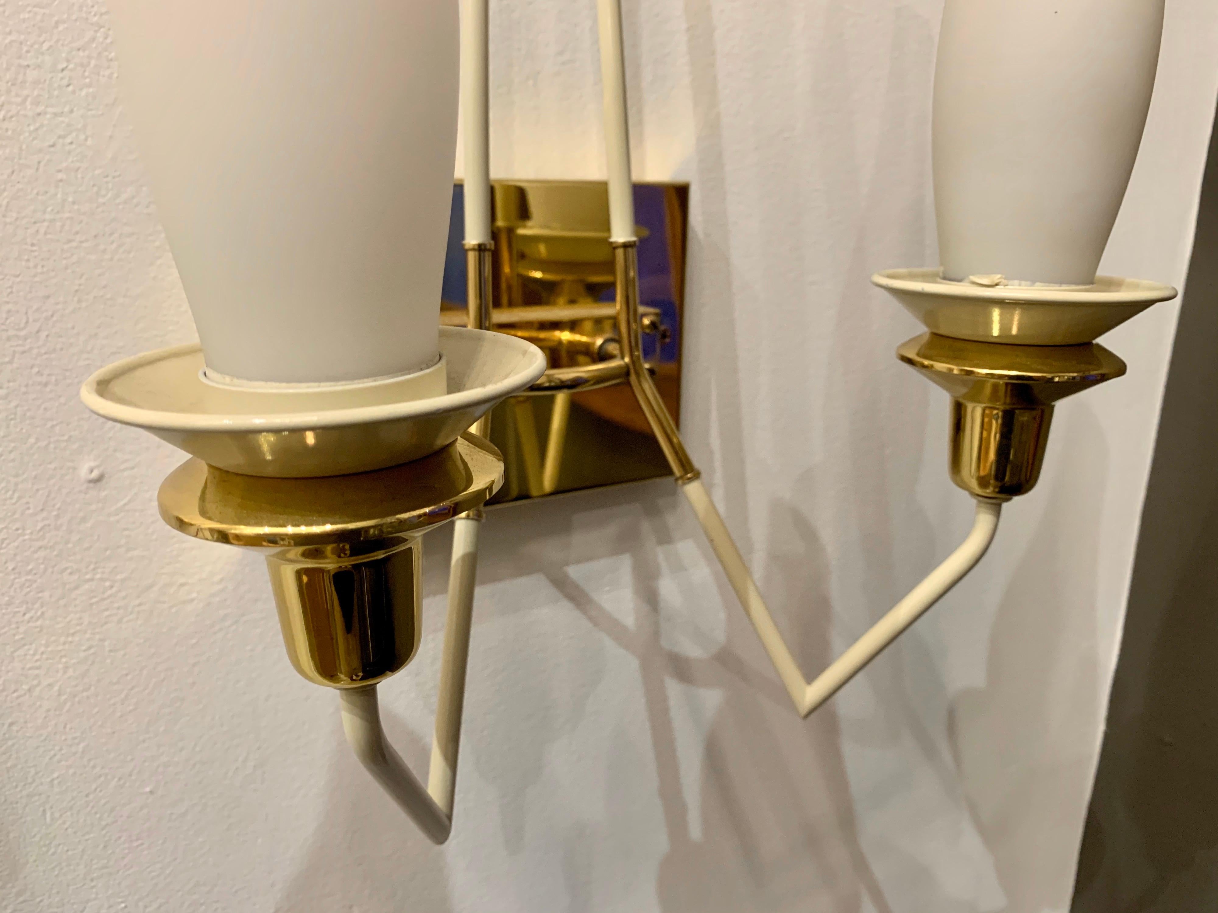 Pair of Mid-Century Modern Stilnovo wall sconces in high polished brass and off-white arrow-shaped enamel details. Each sconce has two frosted glass diffusers with two sockets. Wattage per sconce (25W per socket and up to 40W per socket if desired).