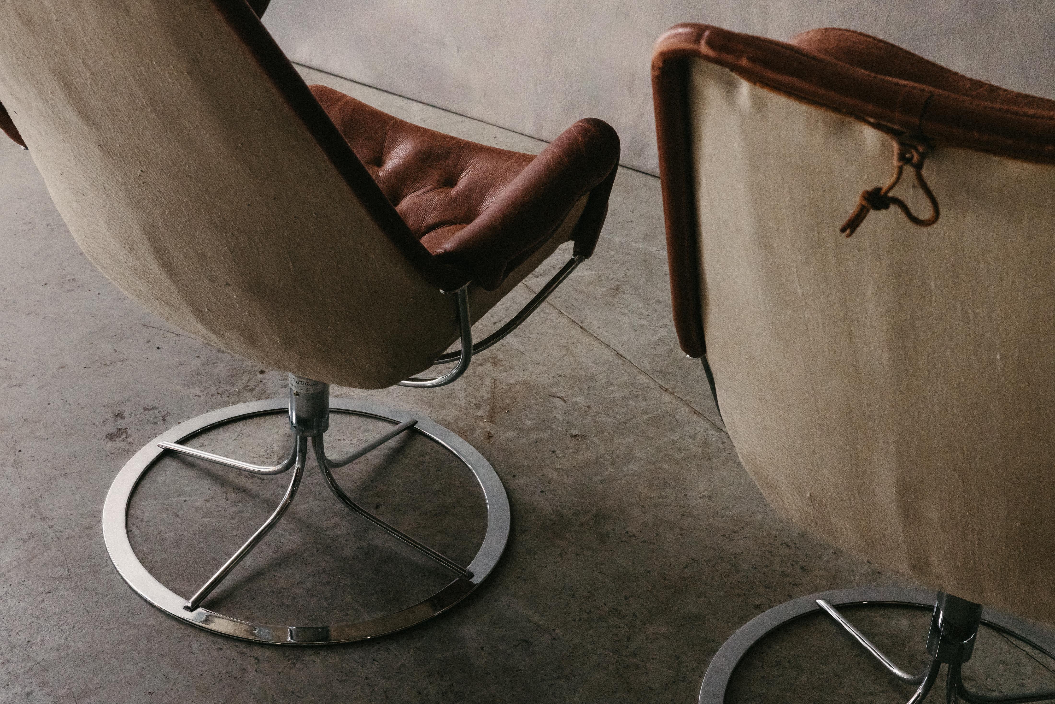 Vintage Paire de chaises longues Jetson de Bruno Mathsson, Suède, circa 1980.  Revêtement original en cuir marron sur une base pivotante en acier.  Belle patine et utilisation.