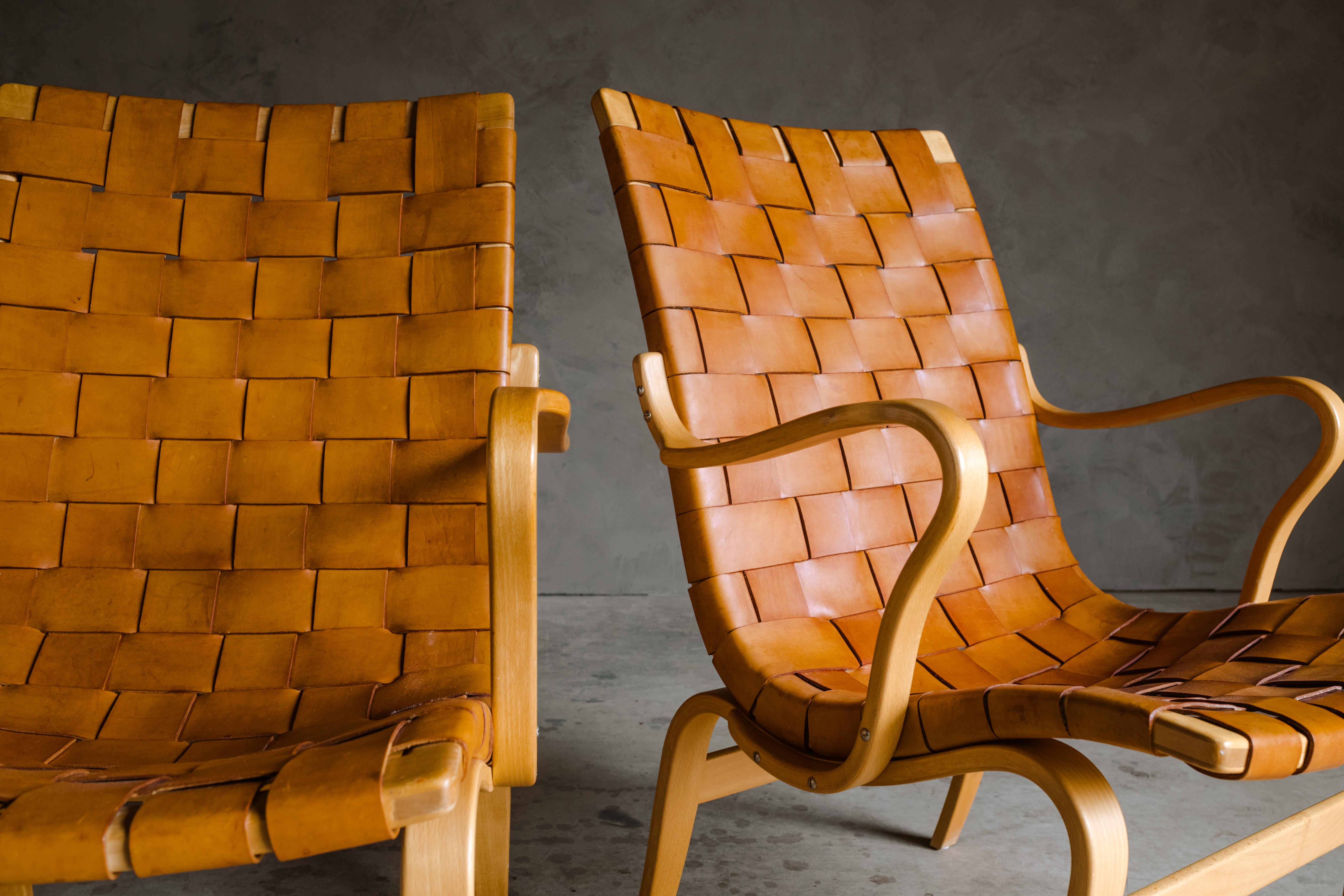 Vintage pair of Bruno Mathsson lounge chairs, model Eva, Sweden 1960s. Original woven leather upholstery on a bentwood frame. Stamped Bruno Mathsson on the back.