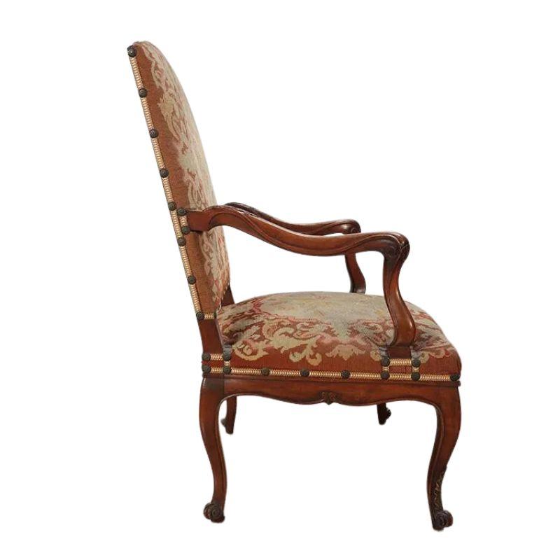 A pair of vintage carved walnut open arm chairs with tapestry upholstery and cabriole legs. The carved French chairs have beautiful carved arms and frame with acanthus leaf detail to the fauteuils arms and seat apron. The cabriole legs end in a