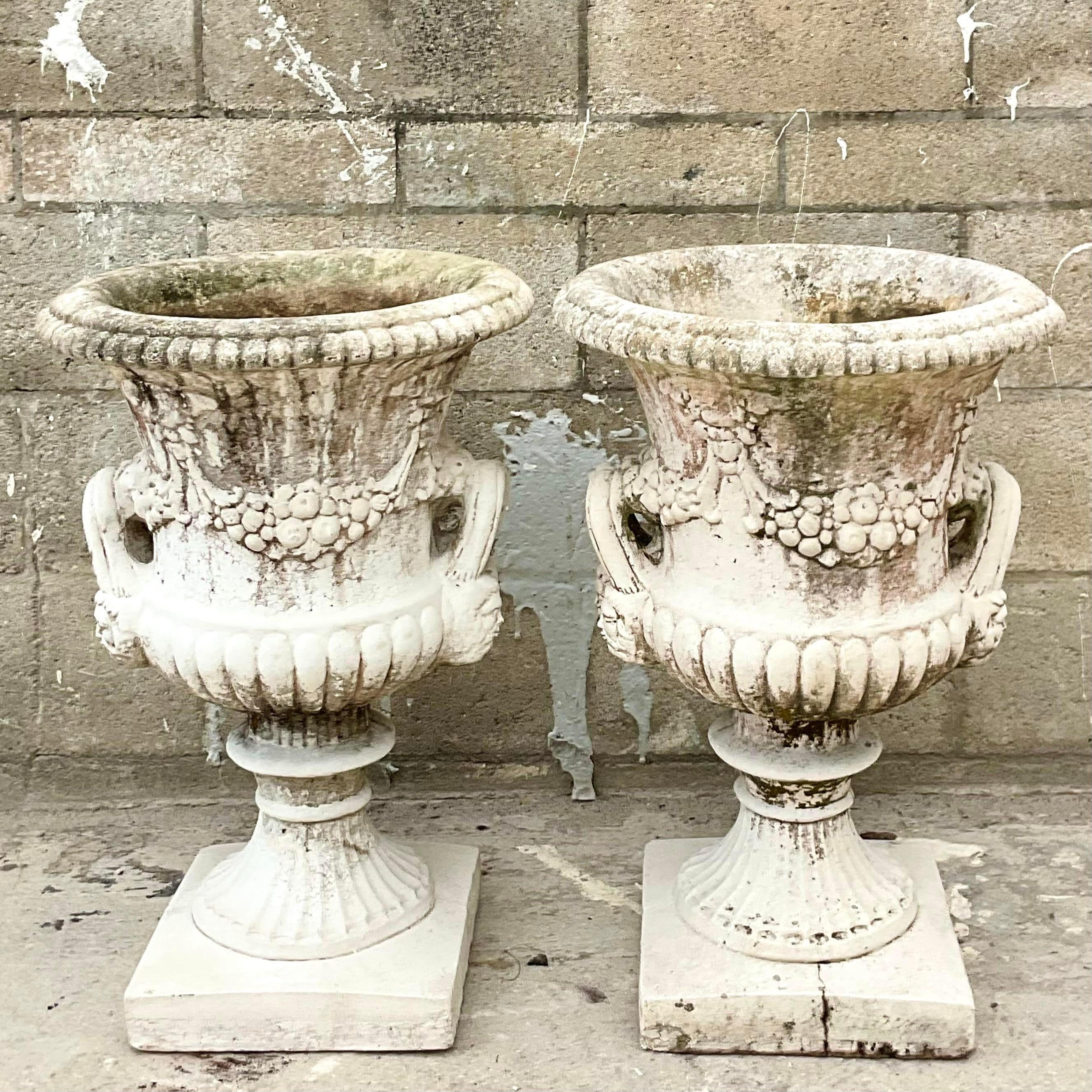 A fabulous pair of large cast concrete urns. Beautiful swag details and large handles. Perfect indoors or outdoors. You decide. Covered with a brilliant all over patina. Acquired from a Palm Beach estate. Acquired from a Palm Beach estate.