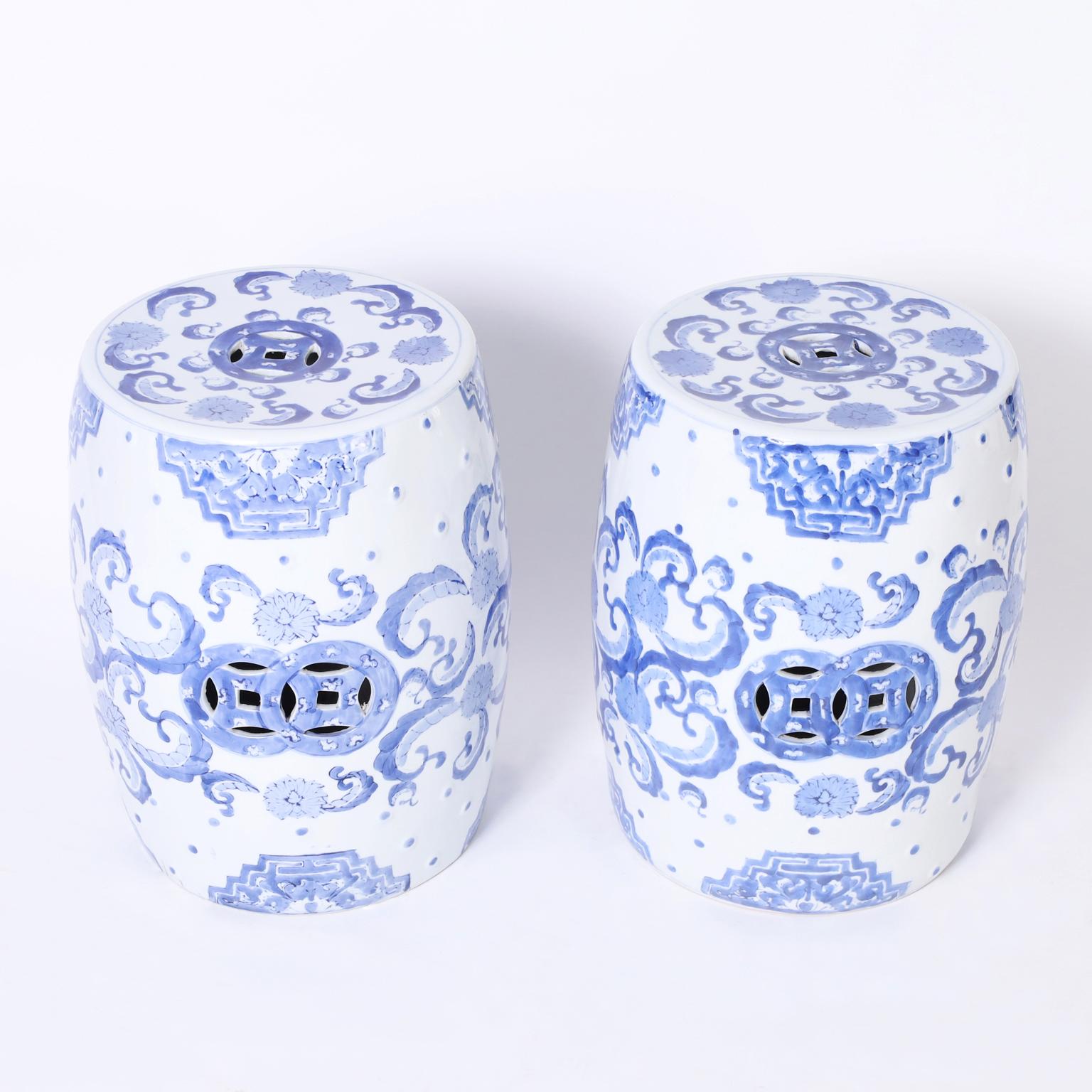 Pair of mid century Chinese garden seats crafted in terra cotta in classic form and hand decorated with charming blue floral designs on a white glazed background.