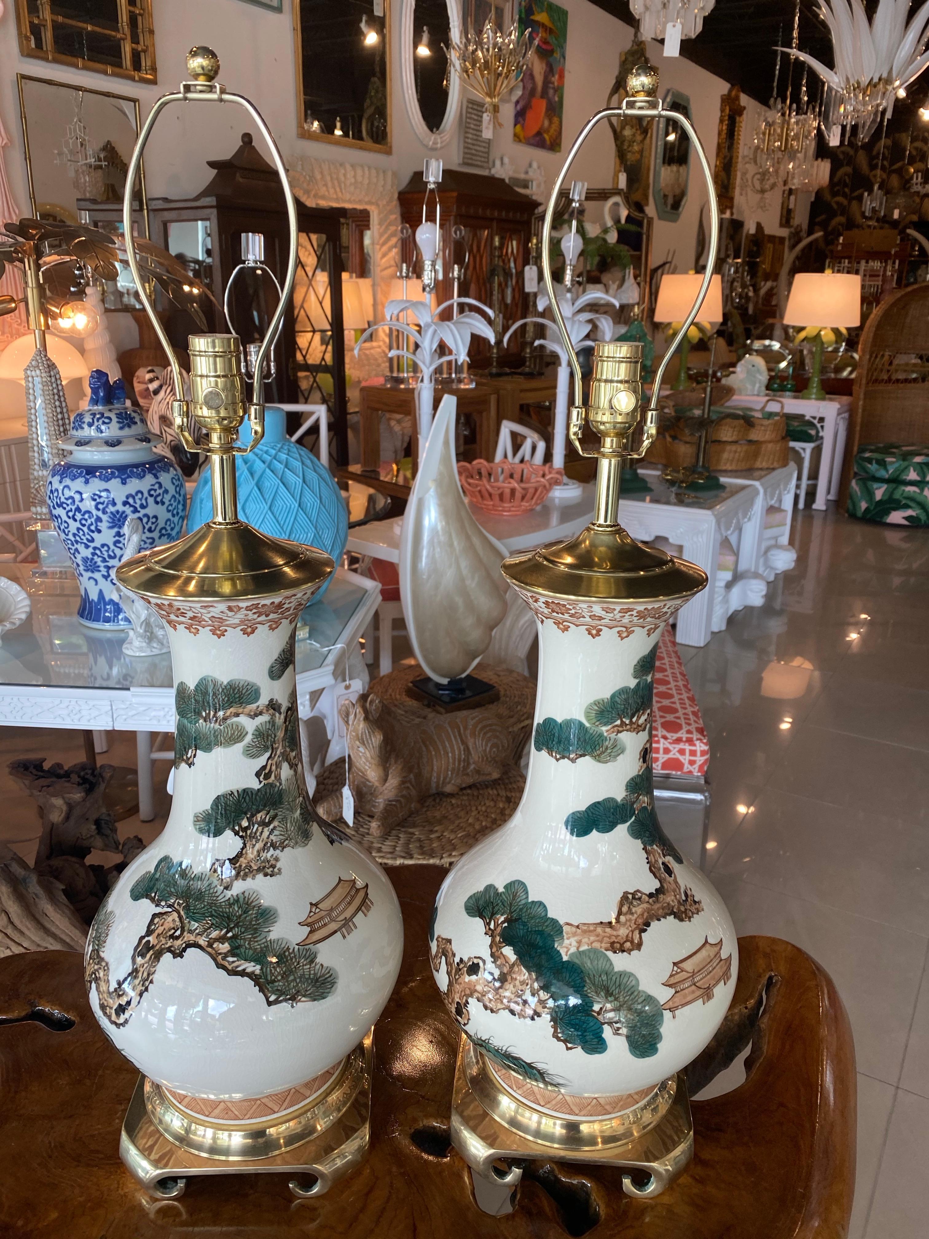 Lovely pair of vintage chinoiserie ceramic table lamps. Lovely design with trees and pagoda house. Newly wired. Original brass Greek key base has been polished. New brass hardware. These have great size and weight to them. No chips or
