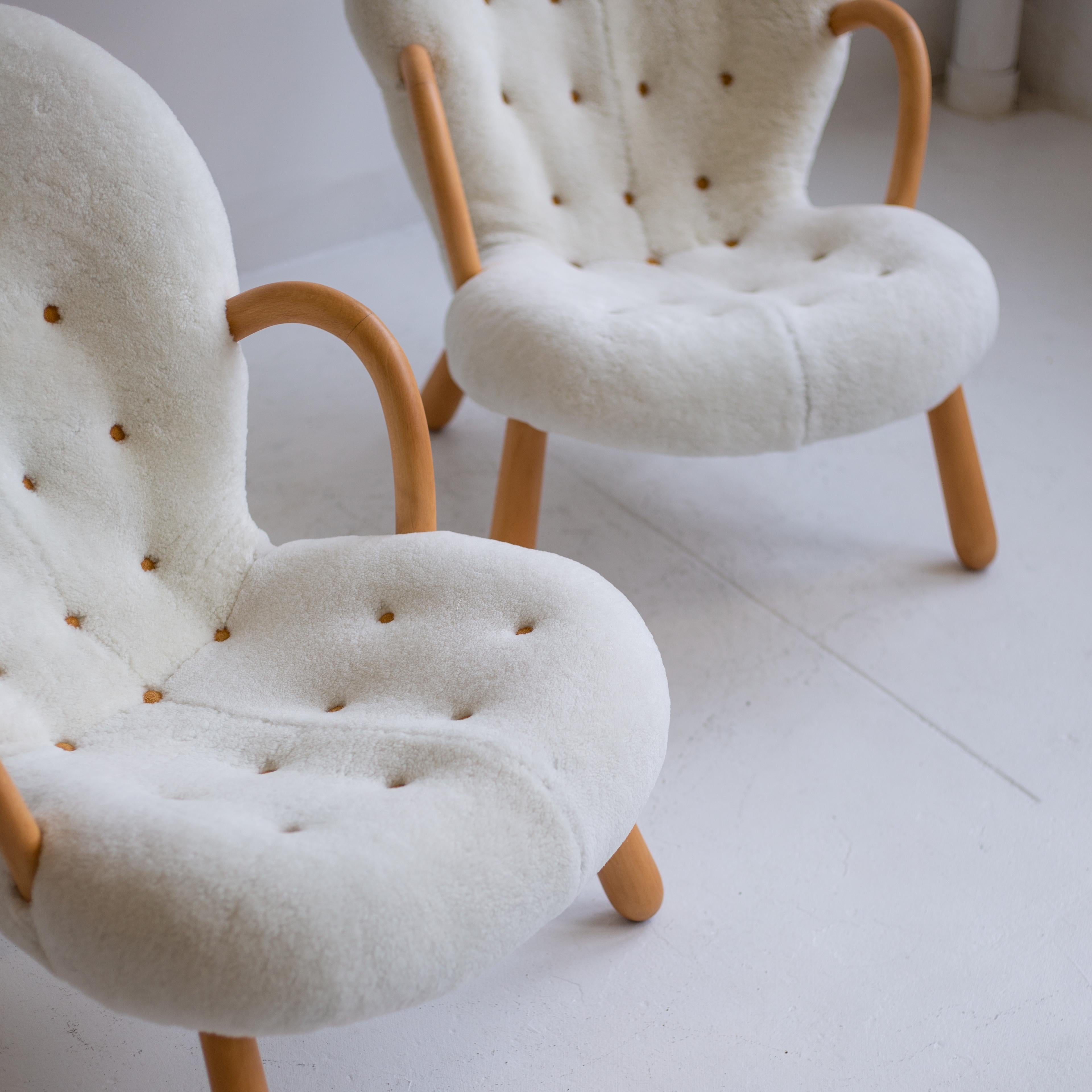 Pair of iconic clam chairs by Philip Arctander newly reupholstered in sheepskin with leather buttons, and wood finish was fully restored recently as well.