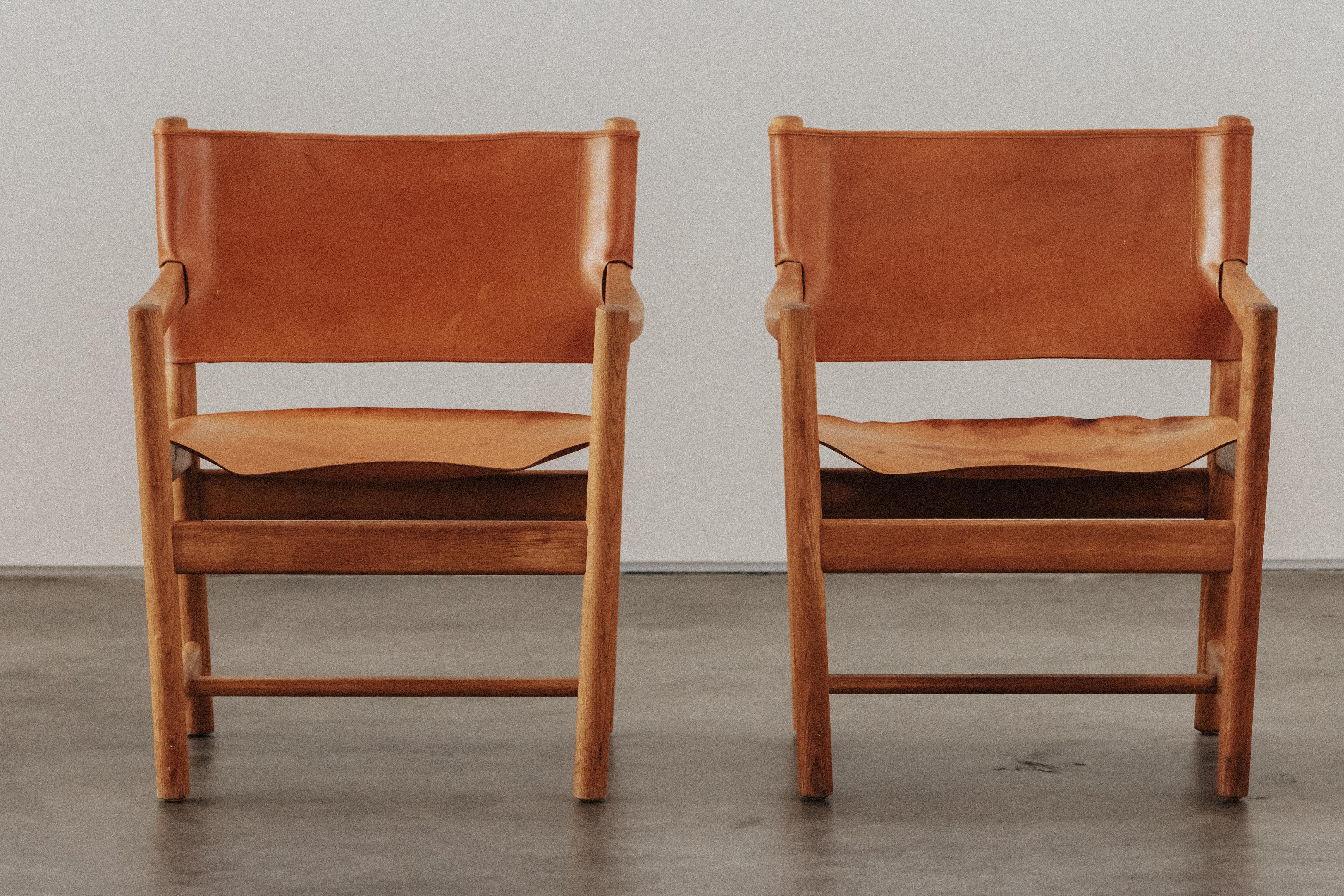 Vintage Pair Of Cognac Leather Lounge Chairs From Denmark, Circa 1970.  Solid oak construction.  Nice patina and use.