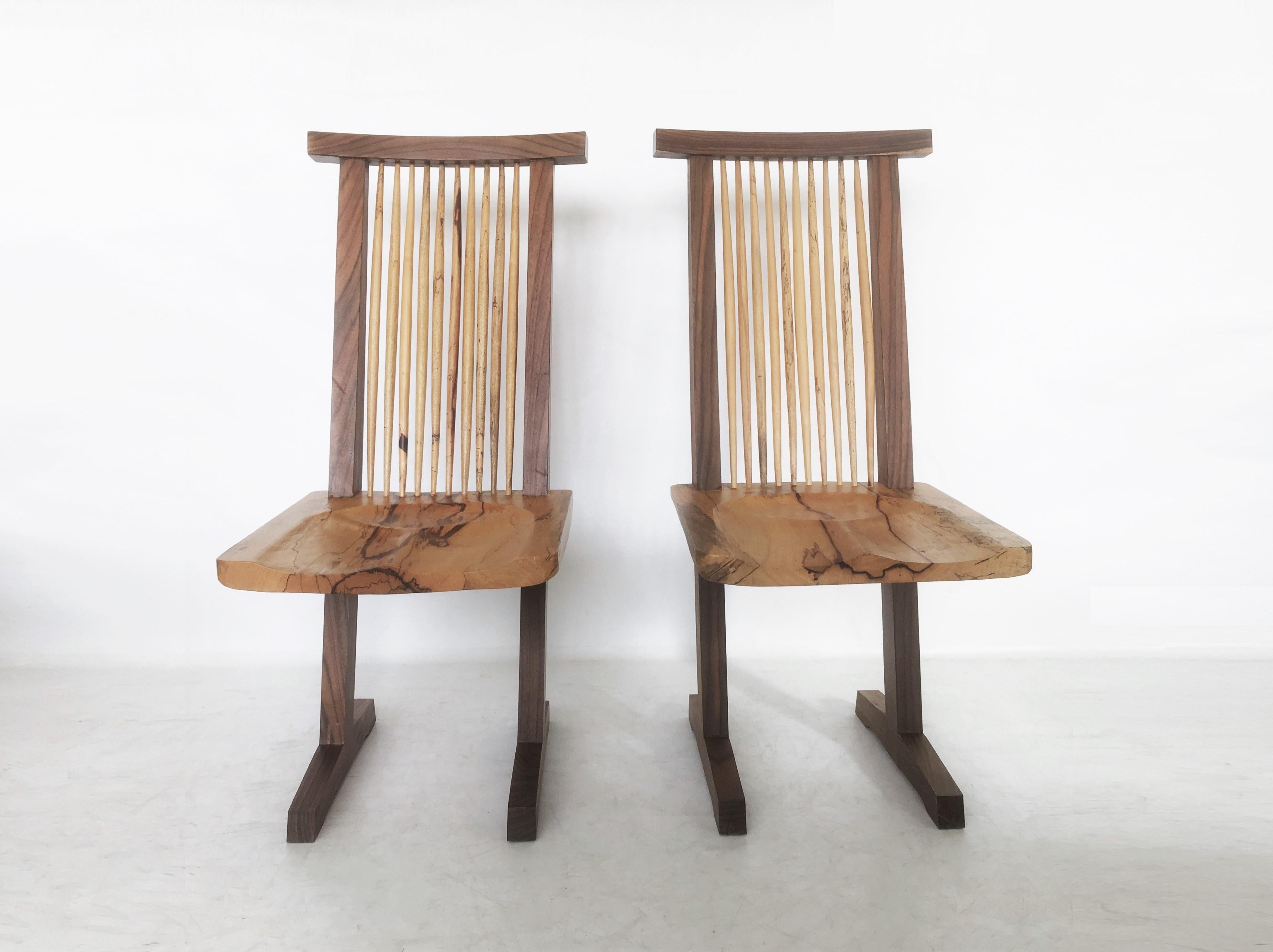 Minimalist elegance! Handcrafted using walnut and hickory conoid chair after George Nakashima. The structure is characterized by the presence of two legs that extend from the feet in the form of a sled, which serve as uprights that support a
