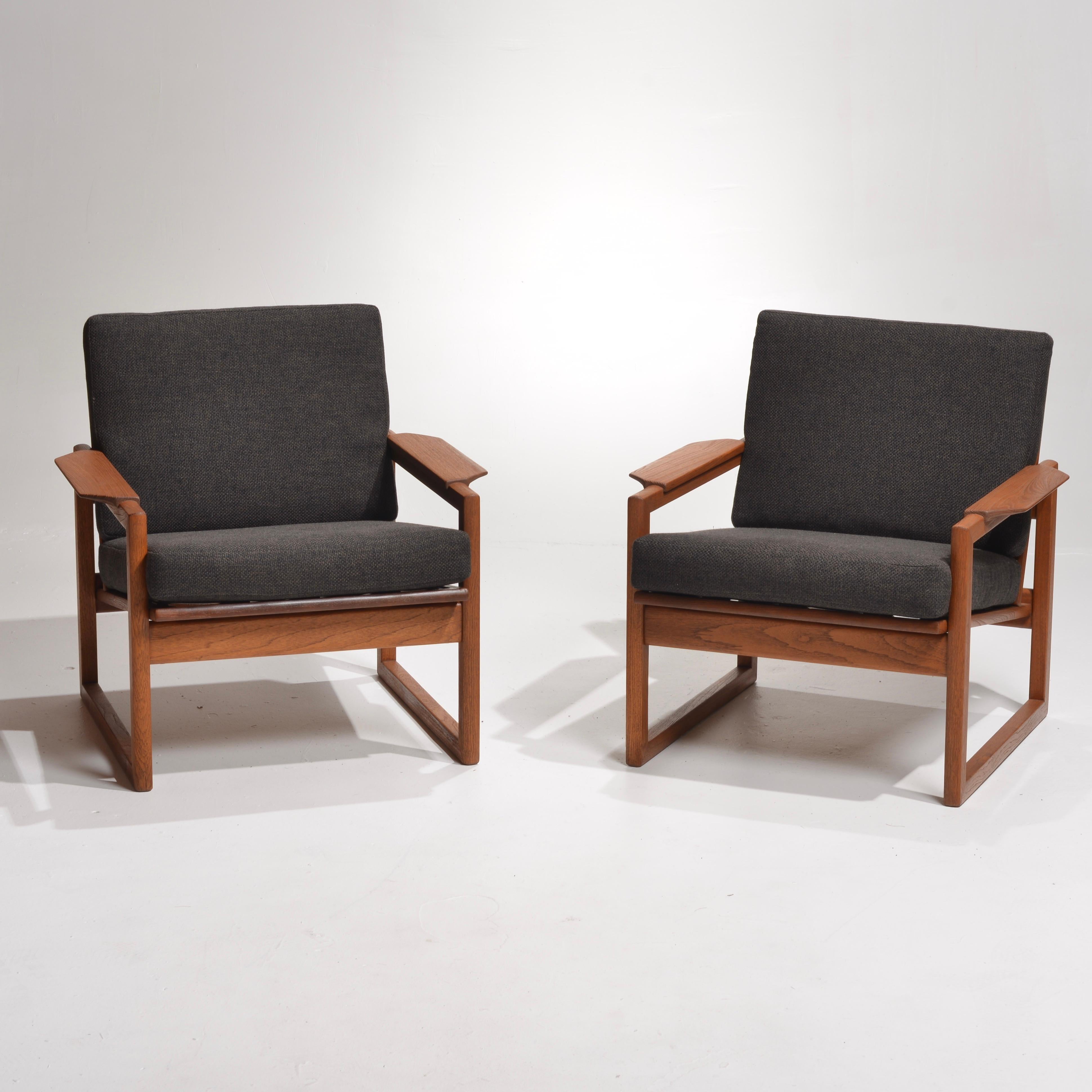 Mid-Century Modern pair of lounge chairs in teak designed by Sven Ellekaer, imported by Selig, Denmark. Features sculptural armrests with a slatted backrest support that can be displayed from all angles. Slate color fabric upholstery over 3.5 inch
