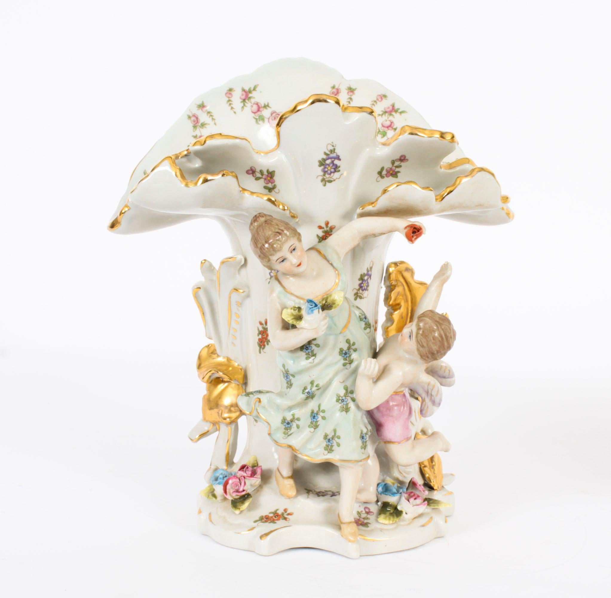 This is a truly magnificent pair of hand painted porcelain spill vases accomplished in the Dresden manner, dating from the second half of the 20th century.

Each vase features a maiden with a winged cherub in high relief hand painted in pastel hues