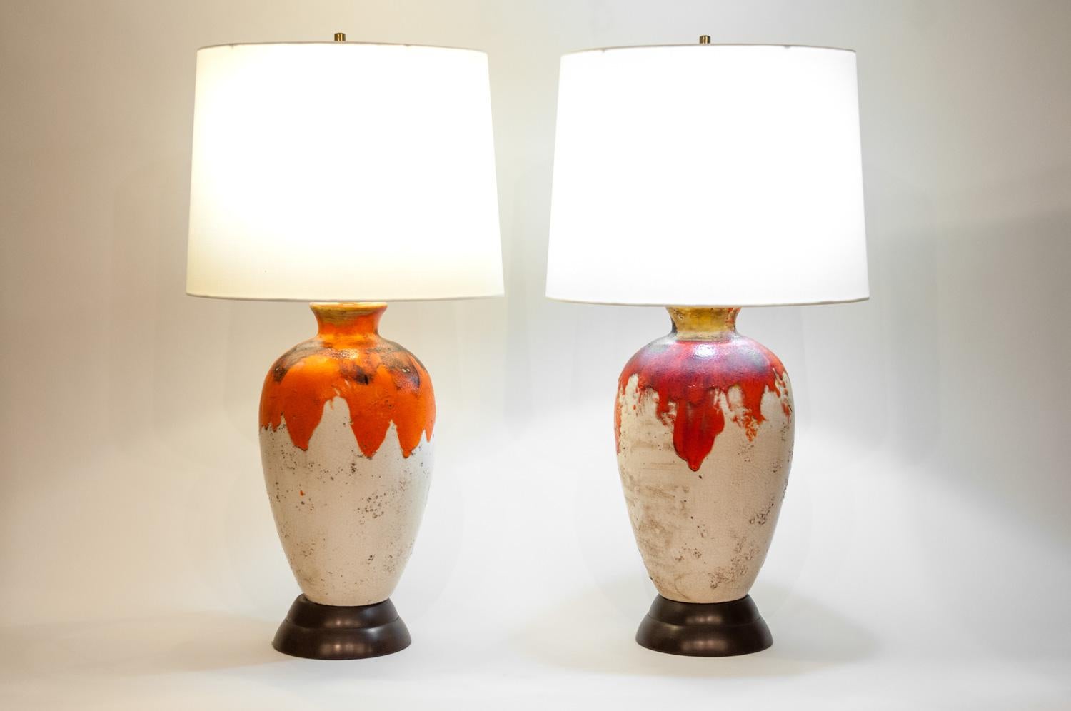 Vintage pair drip glazed porcelain task or table lamps with brass bass. Each lamp is in excellent working condition. Each lamp come with an oval drum shade with silk exterior. Each lamp measure from base to top of finial 33 inches high x 10 inches