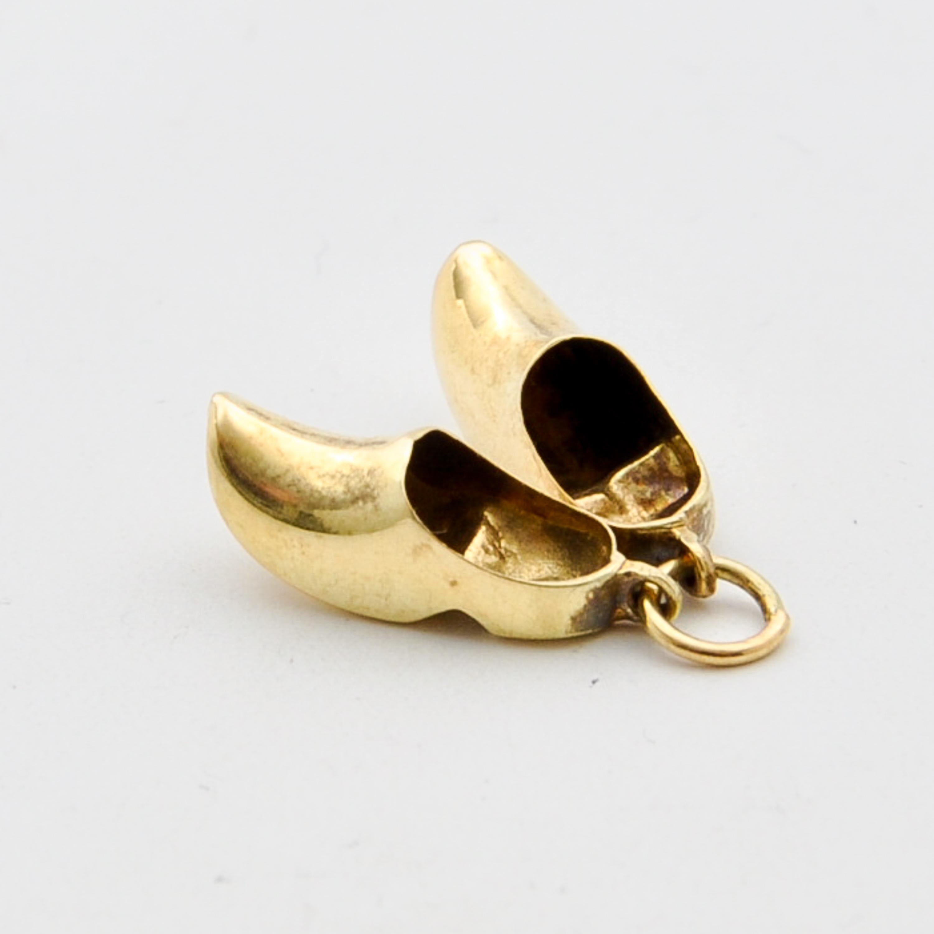 A beautiful pair of vintage three-dimensional Dutch wooden shoes clogs charm pendant. These clogs are nicely polished and made in 14 karat yellow gold. The Netherlands is the country of tulips, windmills and clogs. These Dutch icons, are ideal