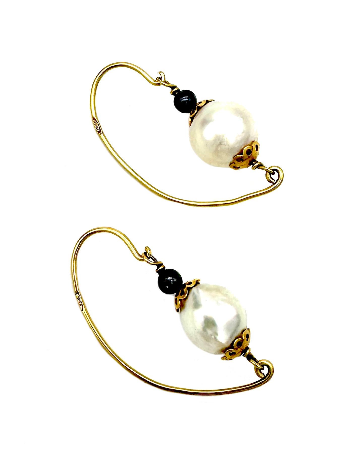The ear hoops were created in the last quarter of the 20th century. They are marked 750 on the ear shaped gold wire. Each ear hoop features a large white cultured pearl with convex golden rosettes on either side that are threaded together with