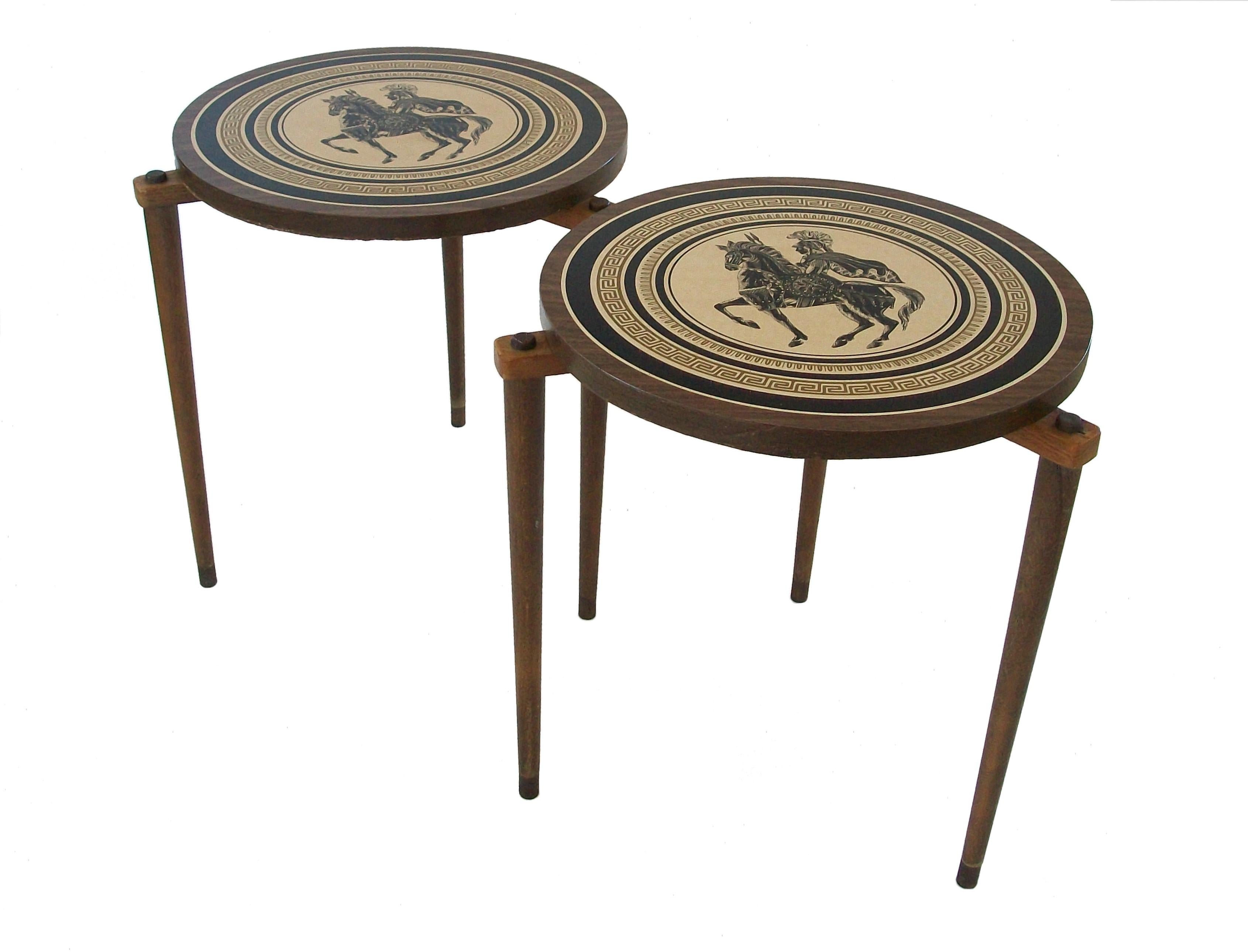 Vintage pair of Fornasetti style occasional or cocktail tables - printed plastic laminate tops and trim - turned and tapered wood legs with brass foot caps - stackable design with plastic glides to the underside of each table - unsigned - United