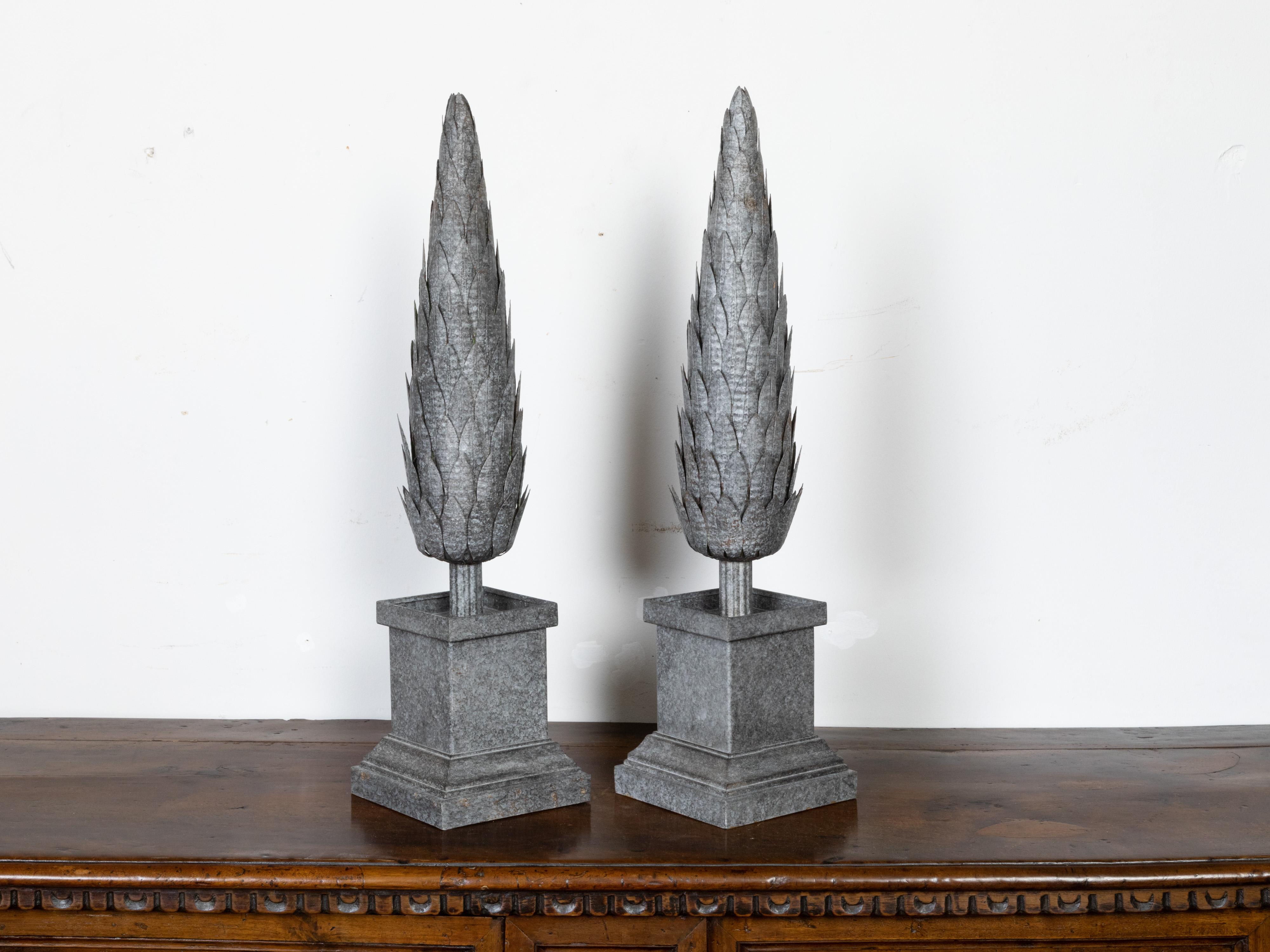 A pair of French vintage zinc topiaries from the mid 20th century, with stepped bases. Created in France during the midcentury period, each of this pair of zinc sculptures features a perfectly pruned topiary resting in a square base with stepped