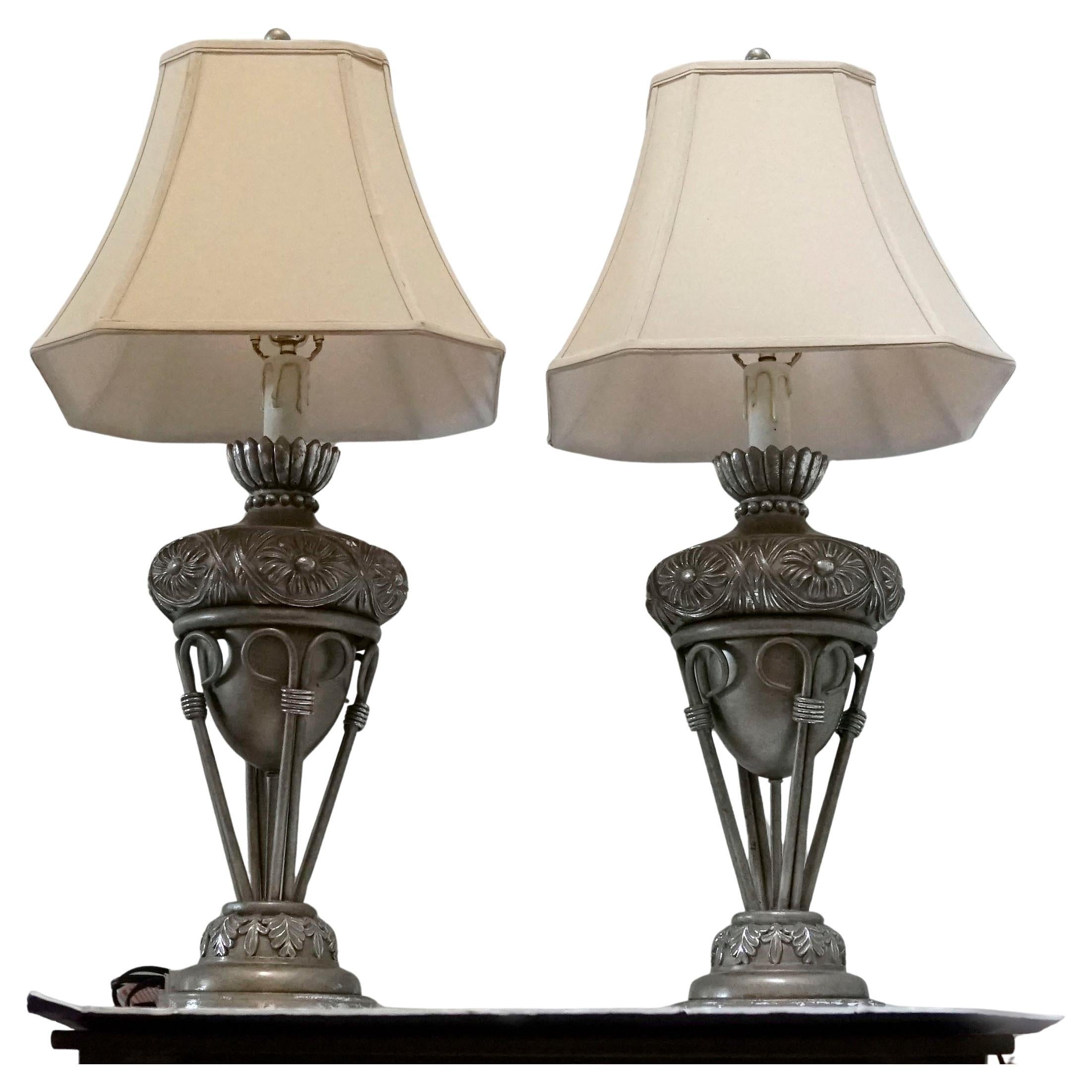 Si tratta di una coppia di lampade a urna in stile neoclassico francese in legno dorato a foglia d'argento con motivi di ghirlande fogliate intagliate a mano. Queste lampade in stile Luigi XVI sono montate su basi a zoccolo in marmo e sono dotate di