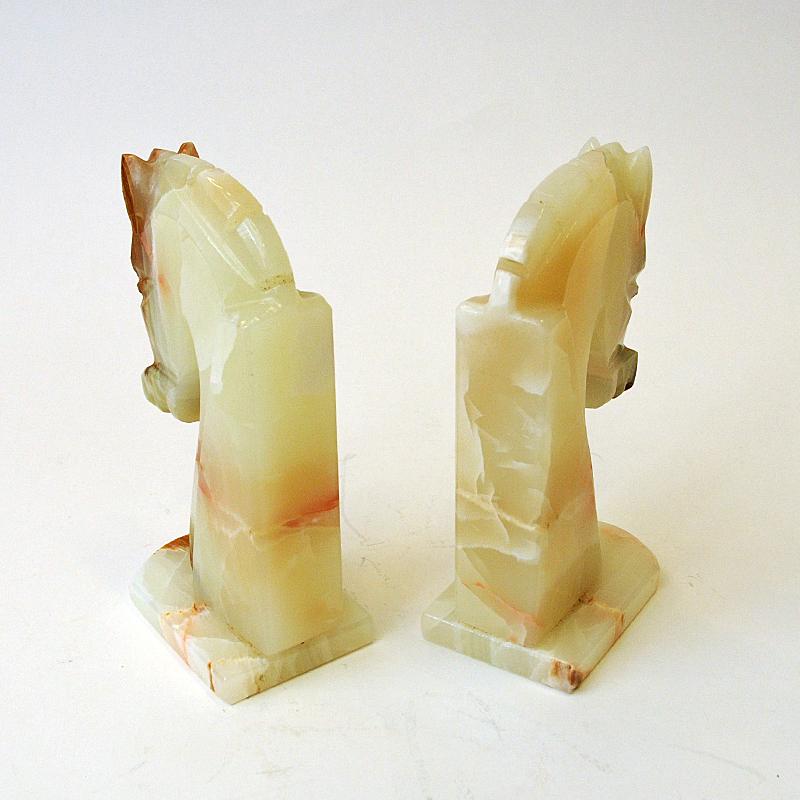 A beautiful and elegant ivory colored pair of vintage onyx stone horse head sculptural bookends with bowed heads. Lovely marble pattern effects. From Italy 1970s.
These handcarved bookends are perfect on the fireplace or shelf, window shield or