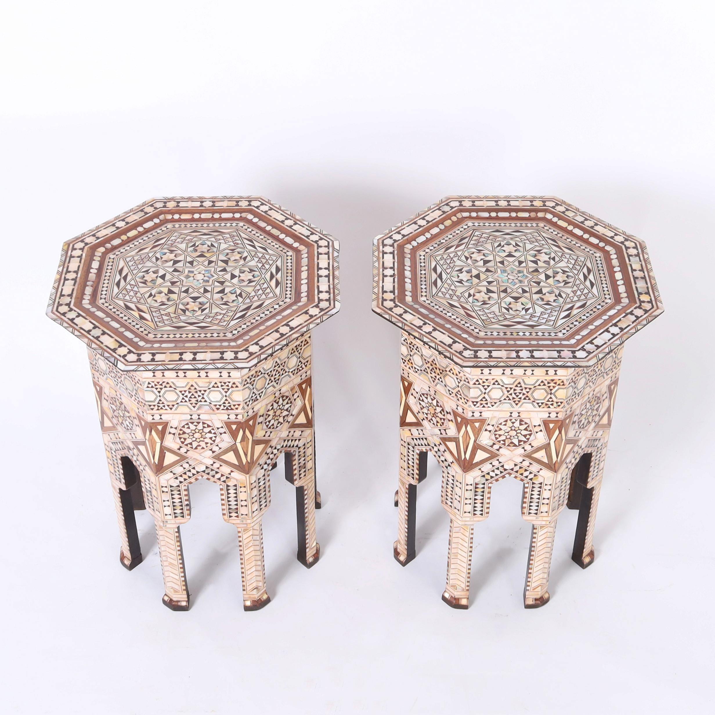 Standout pair of Moroccan stands crafted in mahogany in an octagon form with classic moorish arches and clad in elaborate inlaid marquetry of mother of pearl, abalone, ebony, walnut and bone in geometric designs.