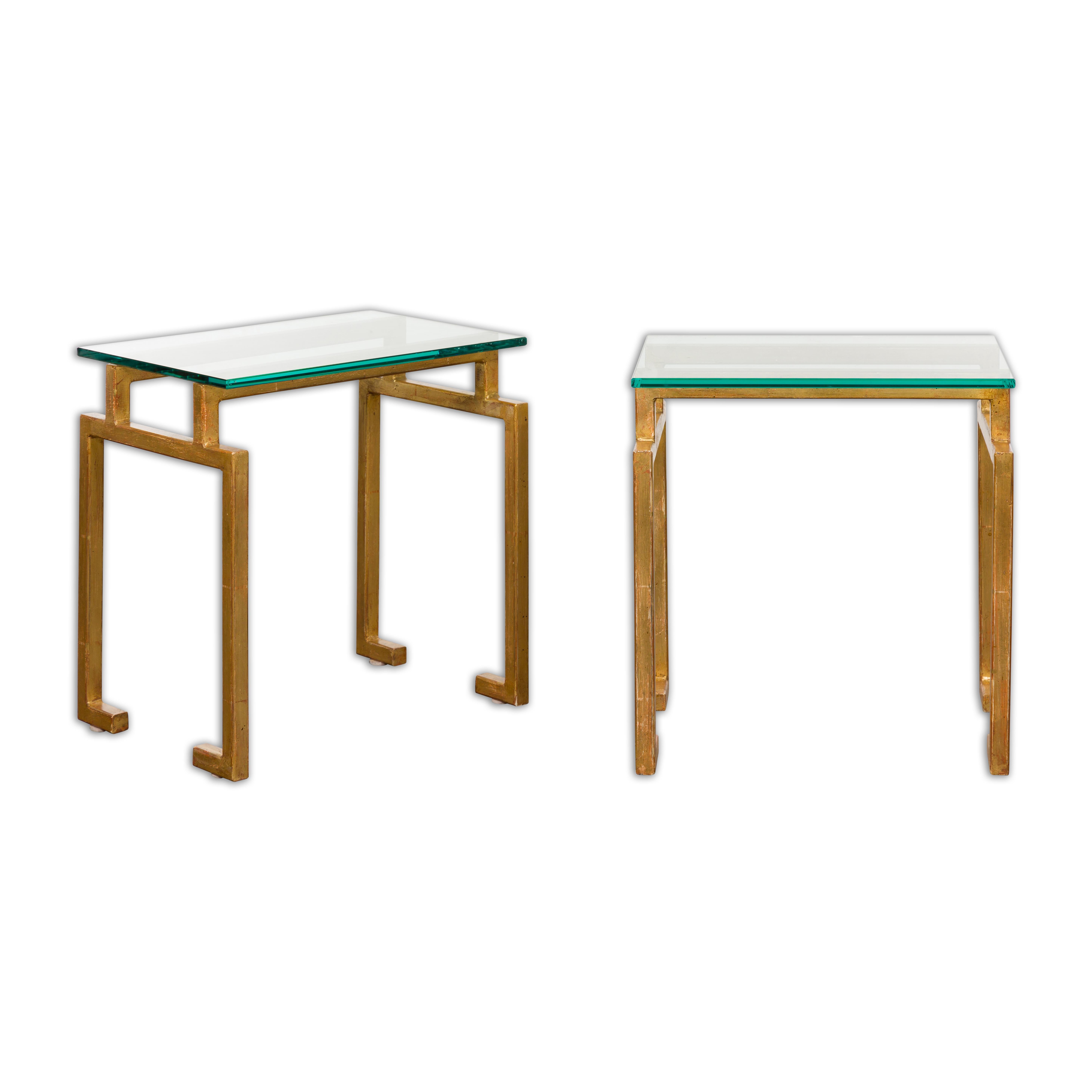 A pair of Italian Midcentury gilt metal side tables with rectangular glass tops and linear silhouettes. Transform your living space with the luxurious addition of these Italian Midcentury gilt metal side tables, a true testament to the lavish yet