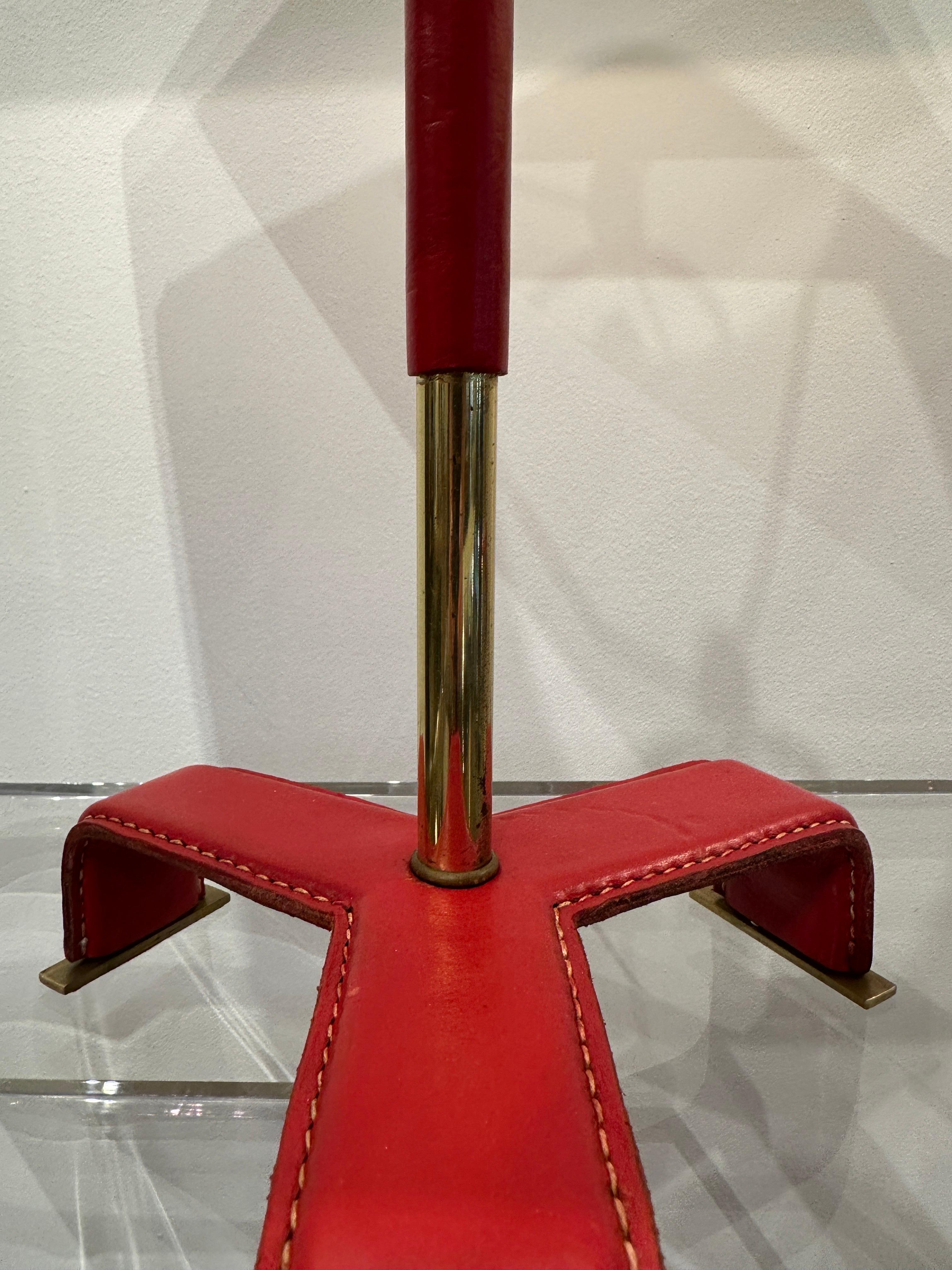These vintage Jacques Adnet style red stitched leather lamps with tri-pod style legs, leather strap to body. Fully updated electrical socket, harp, switch plug and silk wiring. The shades shown are vintage and included with the lamps.  THIS ITEM IS