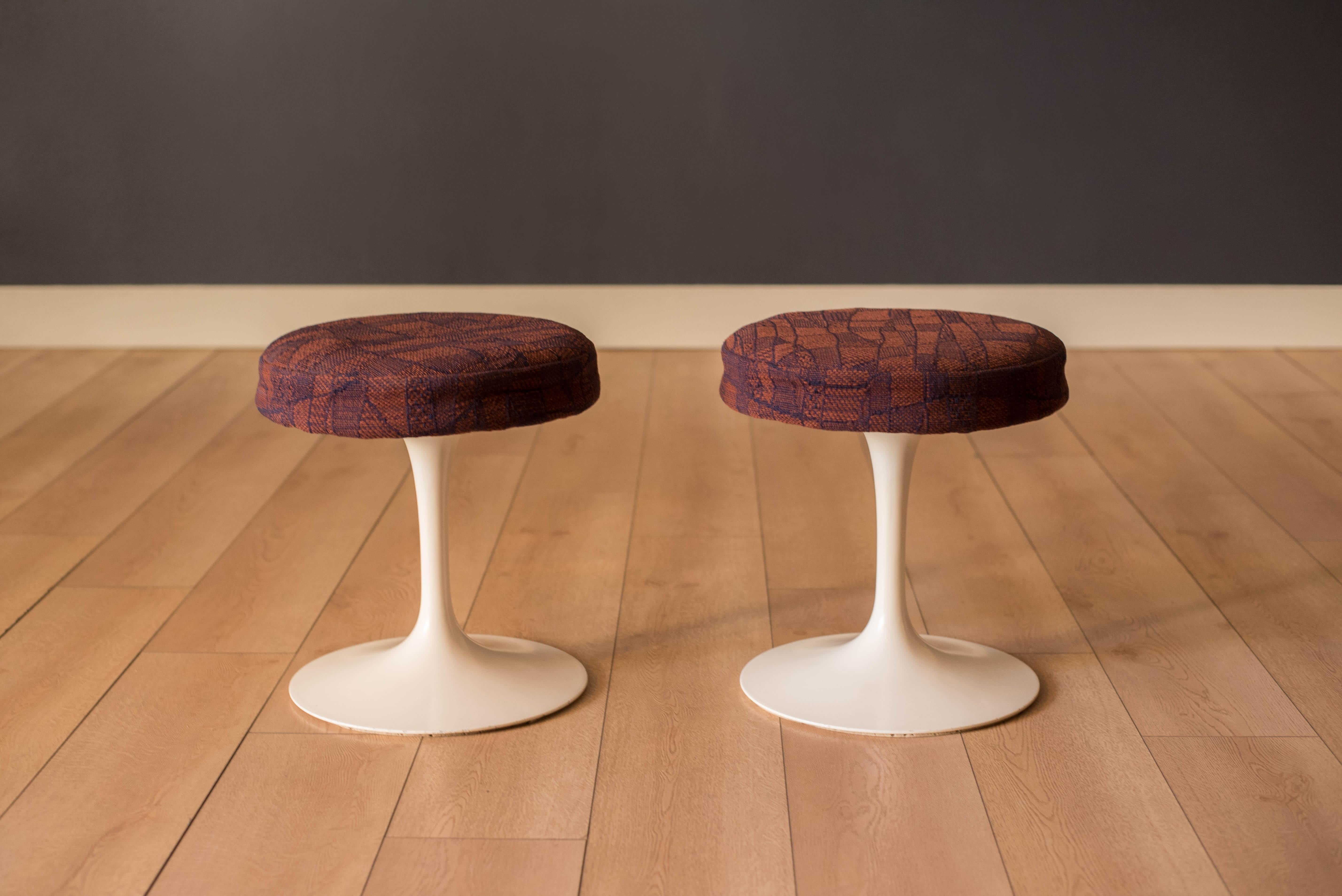 Mid-Century Modern pair of tulip stools designed by Eero Saarinen for Knoll circa 1980's. This versatile set features heavy cast aluminum tulip bases and round swivel seats in an abstract textured fabric. 

Features colors of burgundy red, purple,