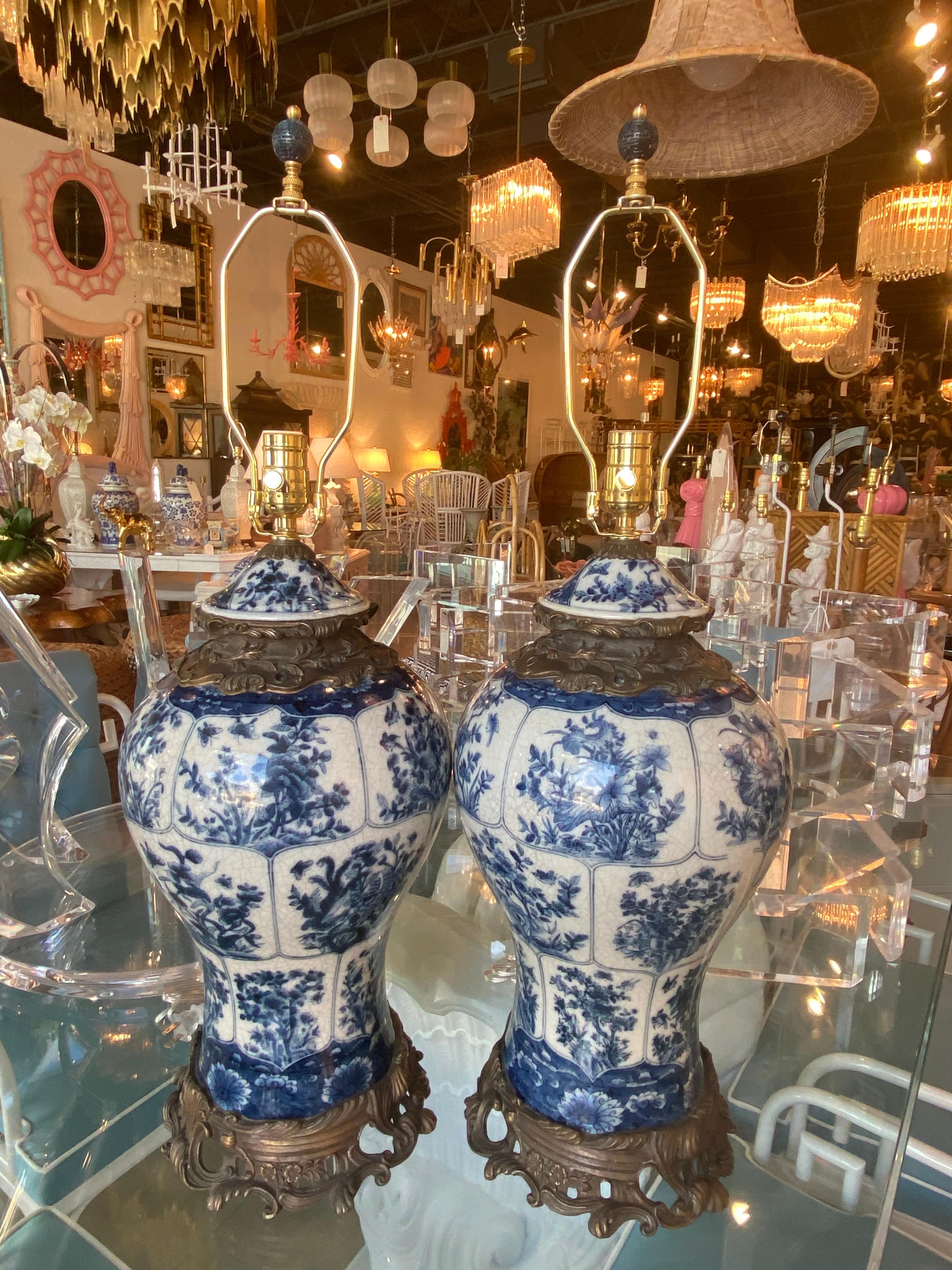 Vintage blue and white ginger jar pair of porcelain lamps. Floral and bird motif. No chips or breaks. These have been newly wired with new brass 3 way sockets. Original blue finial. 
Measures 22 H to socket x 30 H to finial x 10 D.