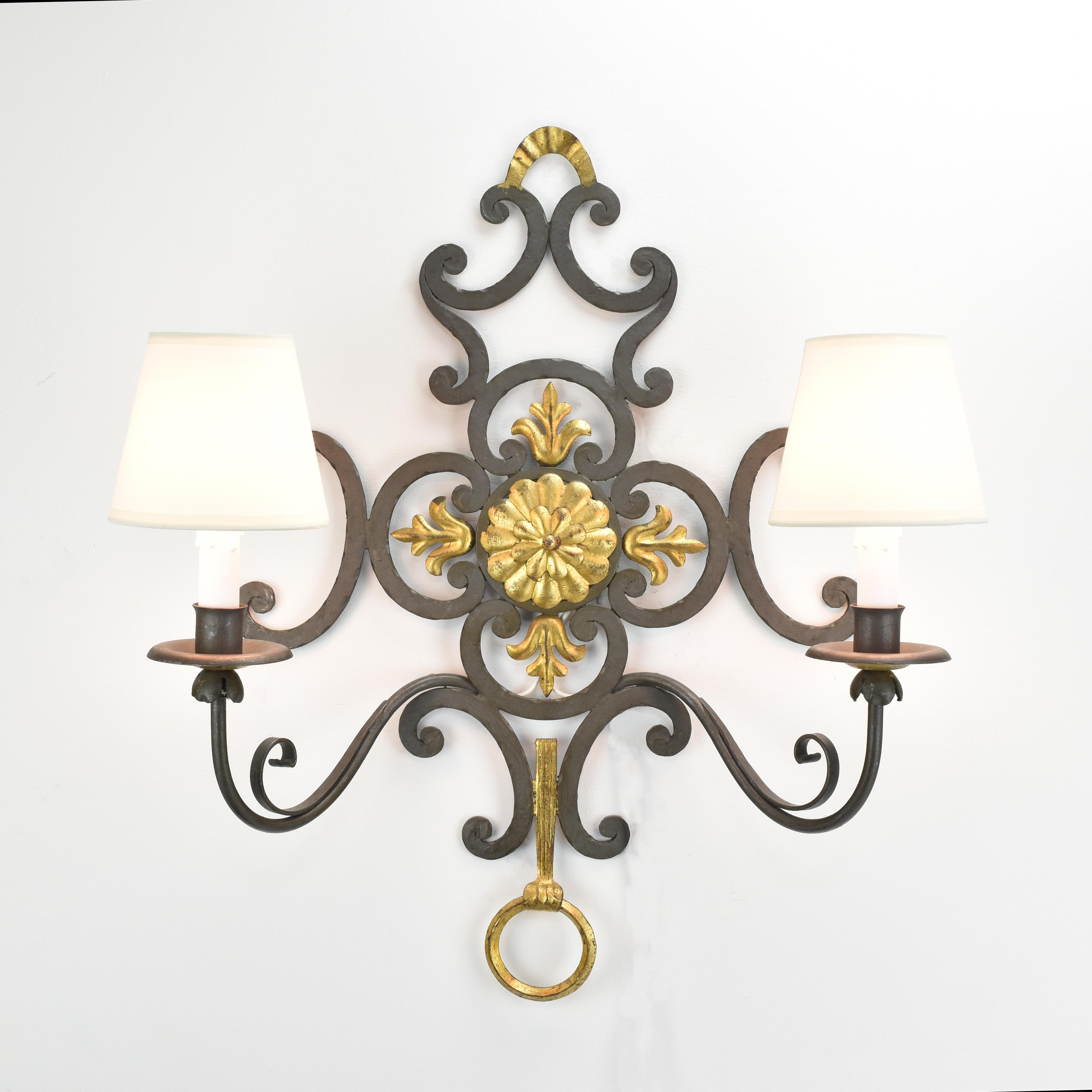Stunning pair of large cold painted and gilt, wrought iron wall sconces in the manner of Gilbert Poillerat.

Each sconce is painted in matte dark verdigris with gilt accents.

This set is a fantastic eye-catcher for your Finca, entrance area or