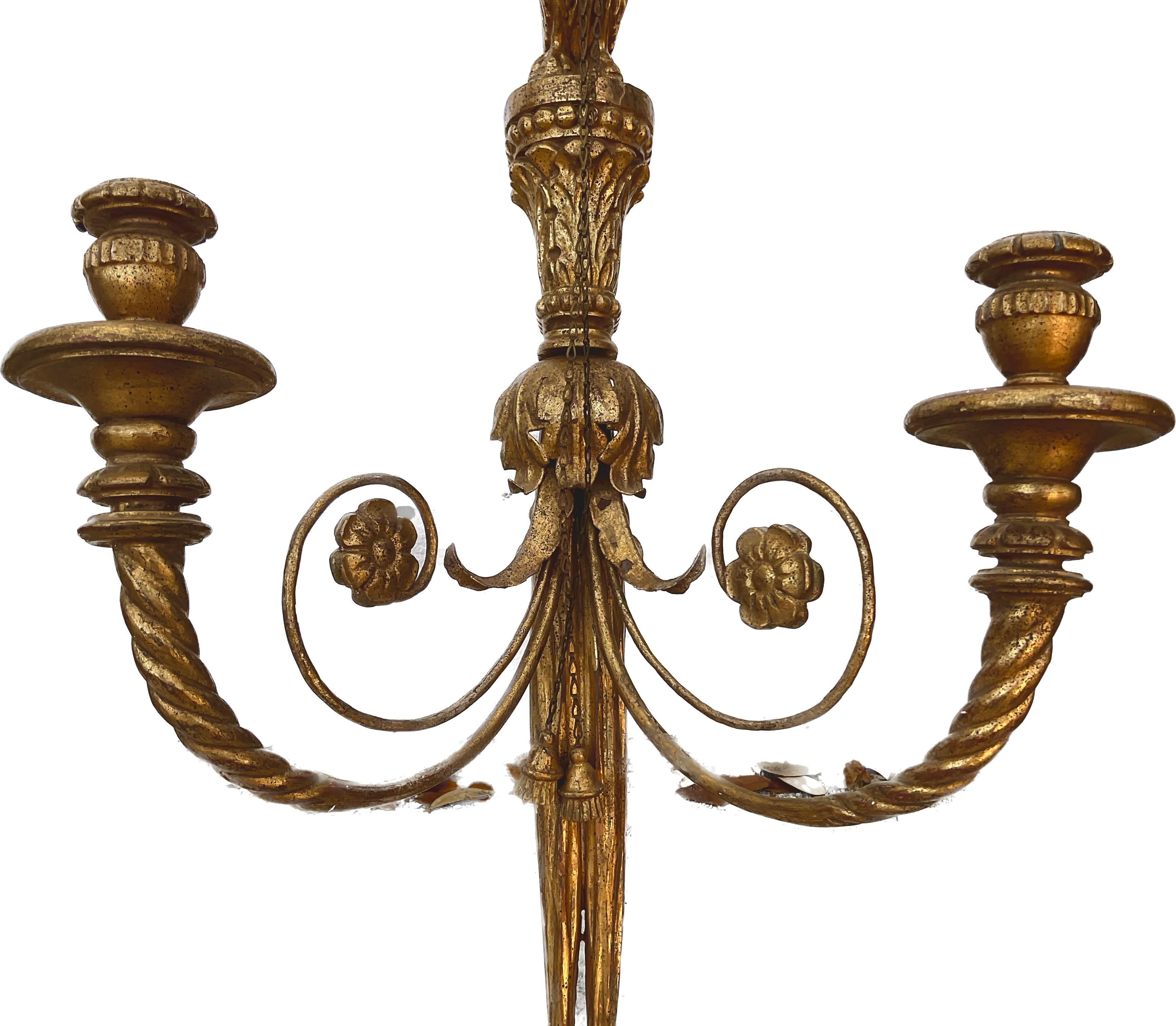 Pair of early 20th century Italian gilt carved wood wall sconces. Each has two arms for candles and a winged eagle, crested with gilded bows.