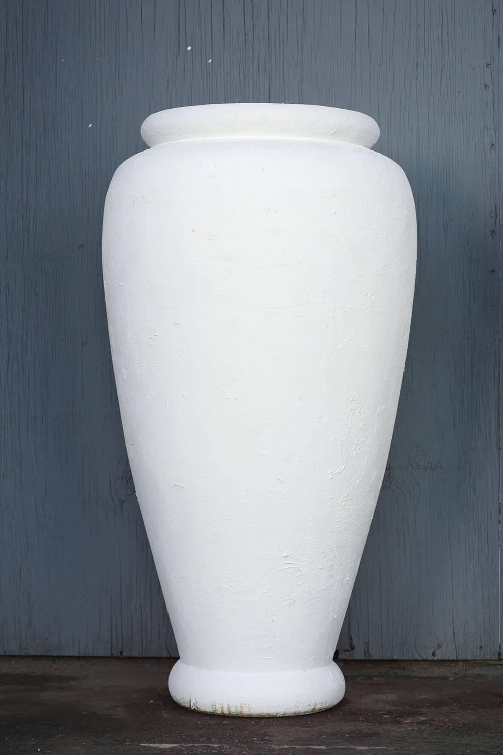 This pair of 1980's Traditional-style patio urns are made from concrete painted an off-white color with a matte finish. The understated profile of the urns is reminiscent of classical Grecian pottery. This pair of patio urns are sturdy, timeless,