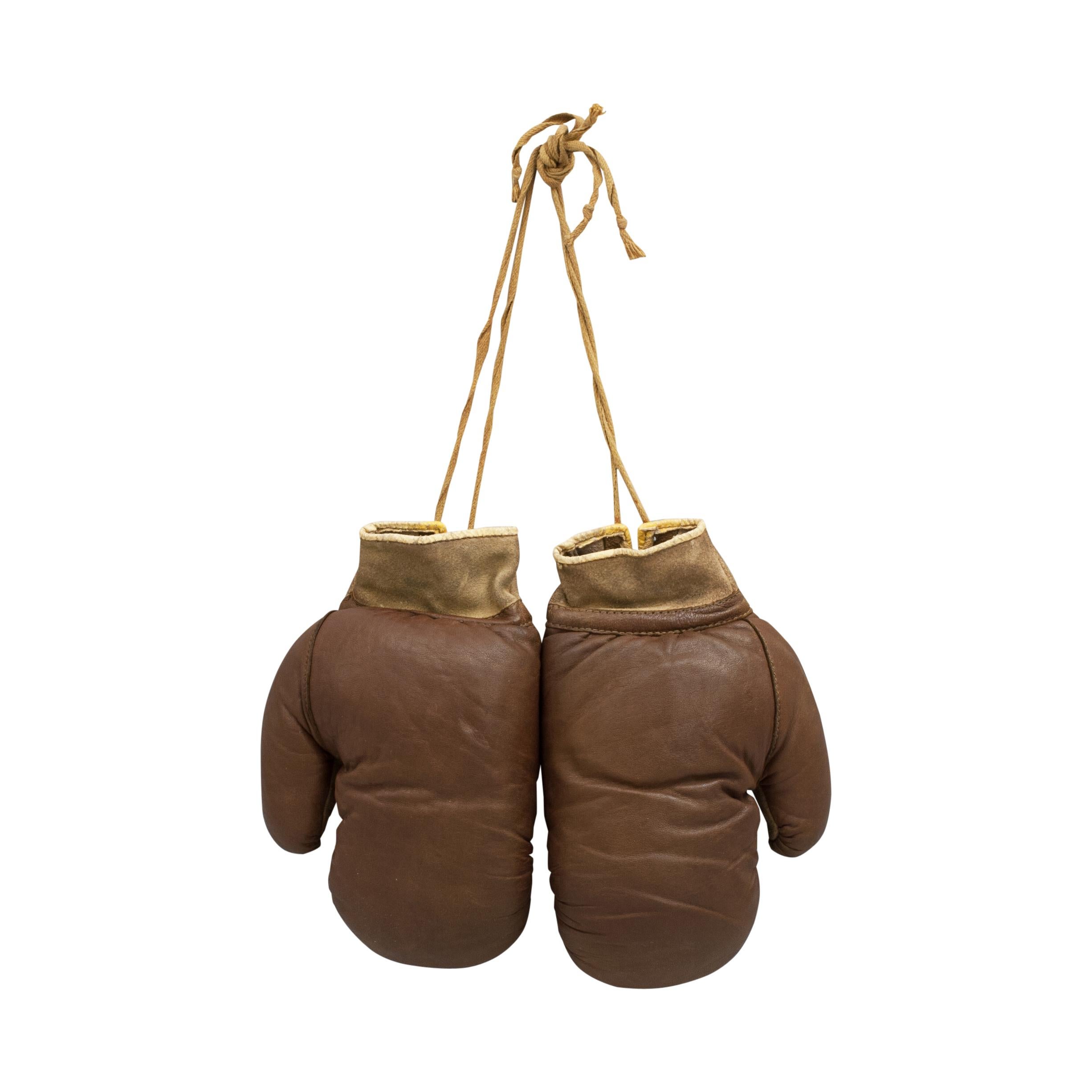 A charming pair of two-tone leather boxing gloves. These gloves are with laced palms, the leather having a nice used patina about them and are in a good condition. A lovely pair of decorative vintage gloves.
  
  