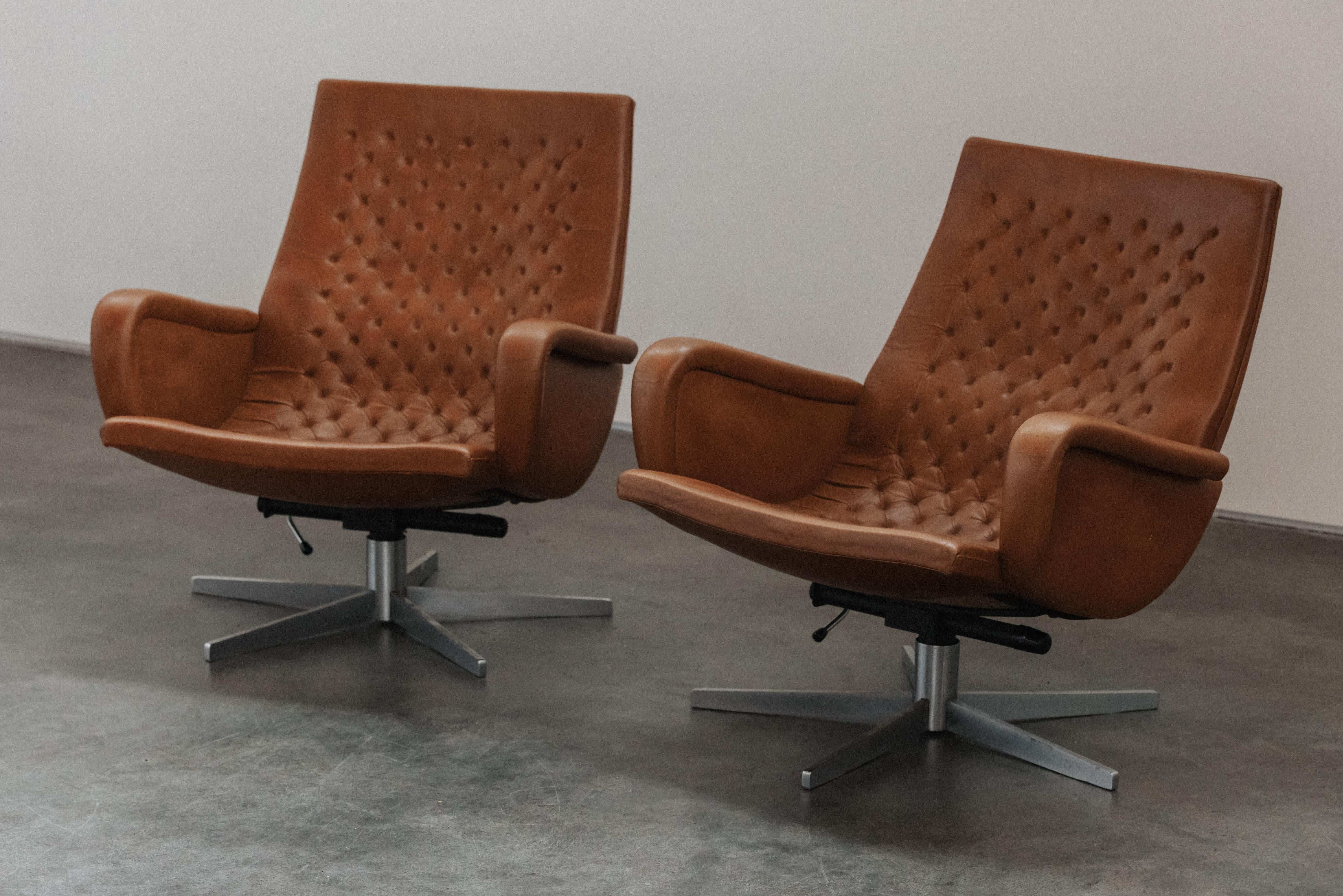 Vintage Pair of Leather Lounge Chairs By De Sede Switzerland, Circa 1970s.  Revêtement original en cuir fauve sur une base pivotante en acier.  Excellent état.