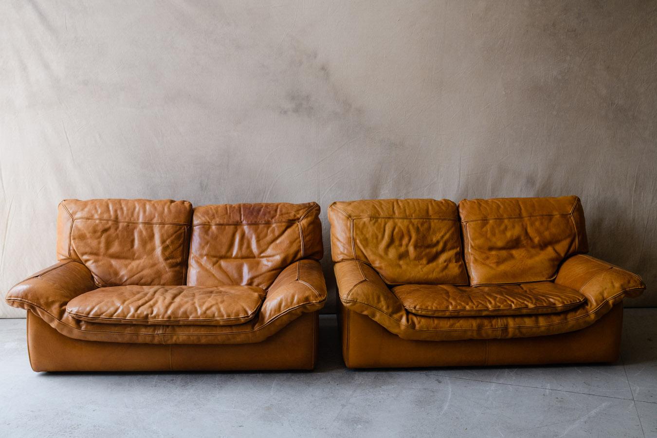Vintage pair of leather Roche Bobois sofas from France, Circa 1970. Unusual pair in cognac leather with an amazing patina to the leather. Marked Roche Bobois under the cushions. Extremely comfortable.

We don't have the time to write an extensive