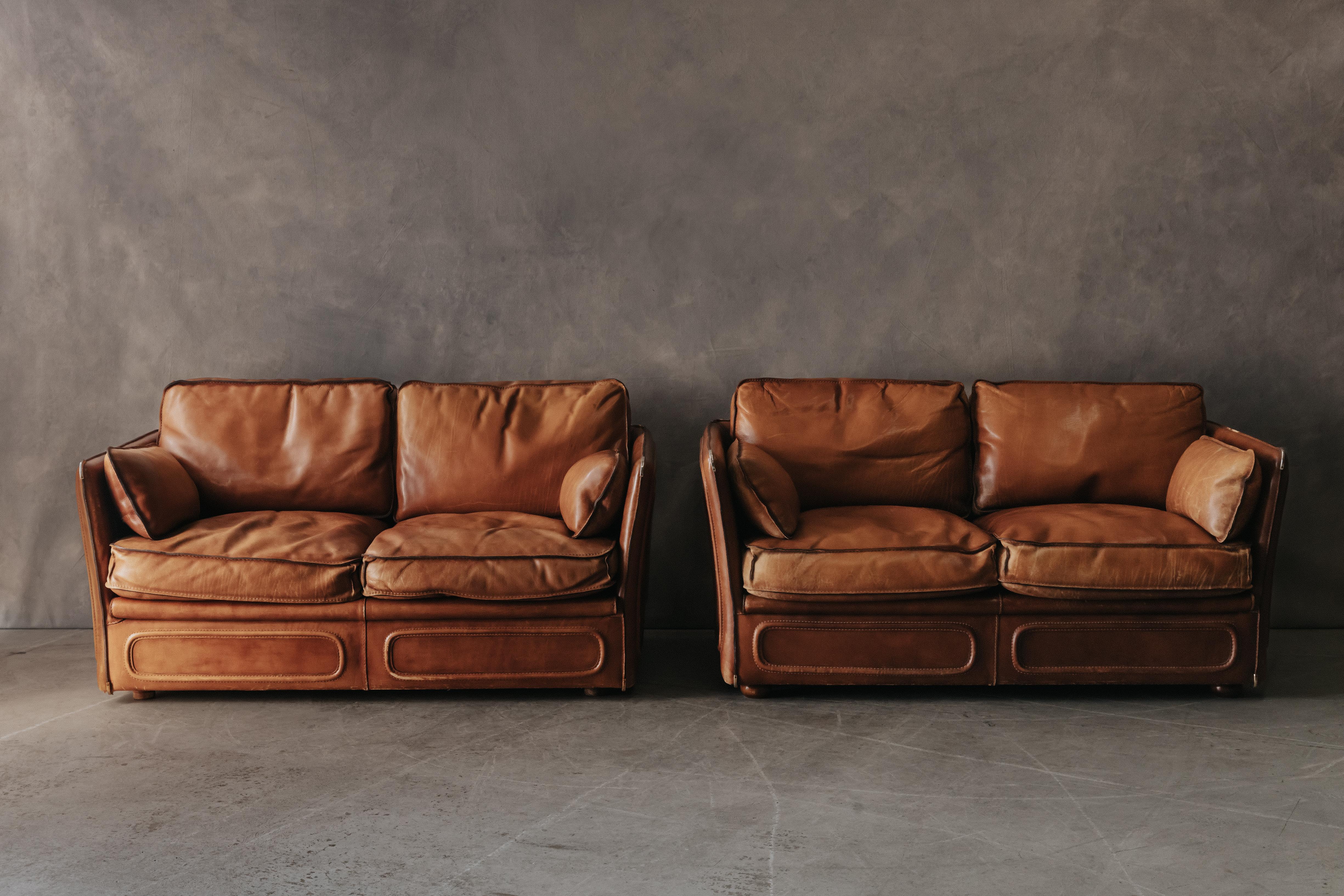 Vintage Pair Of Leather Sofas By Roche Bobois, France, Circa 1970.  Original thick cognac leather upholstery with fantastic patina.  Very comfortable.