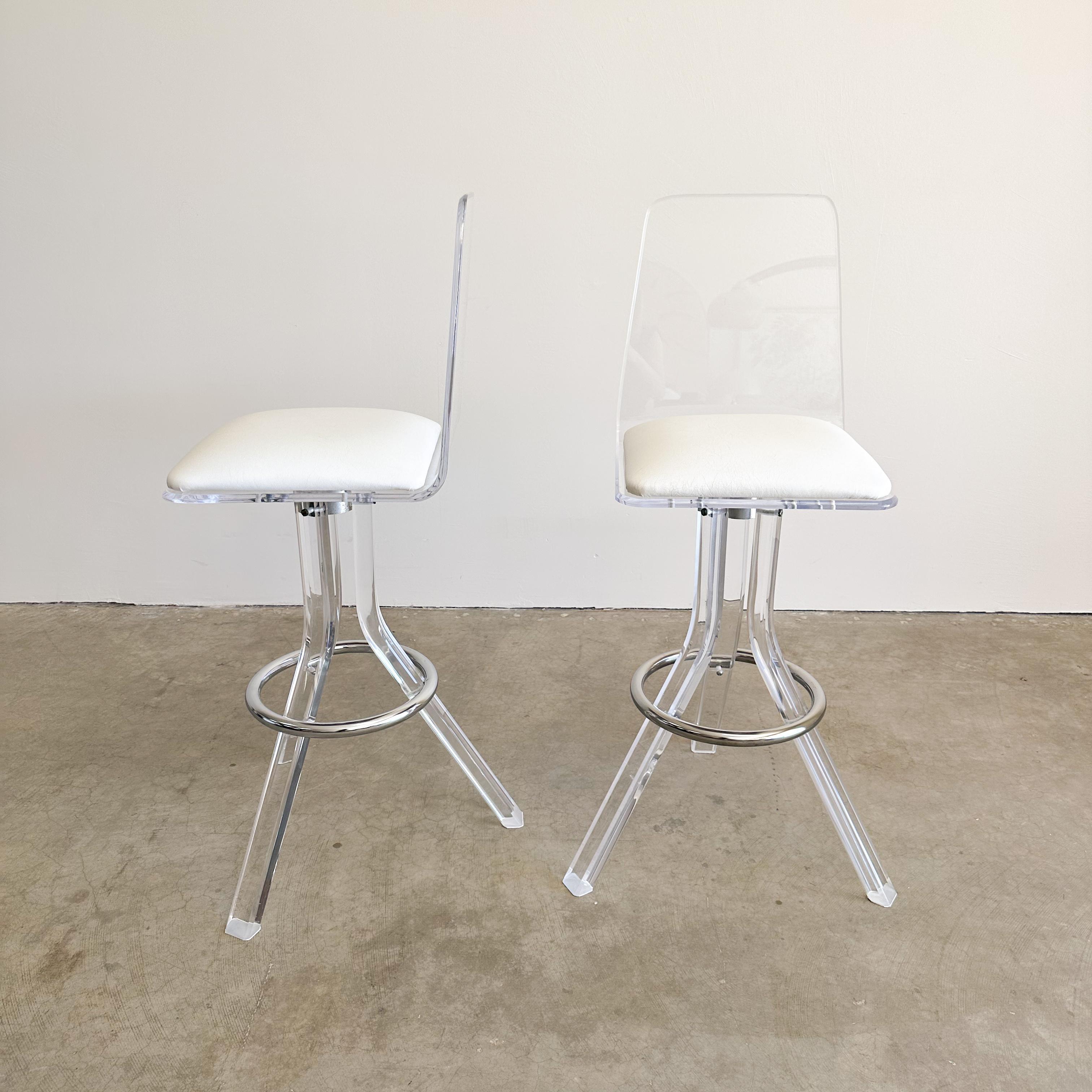 Pair of Vintage Lucite And Chrome Bar Stool. 

The barstools feature lucite construction with swivel functionality, a chrome leg rest, and a seat made of leather or pleather (not sure). 

Color: White 

Measurements: 
Width: 16