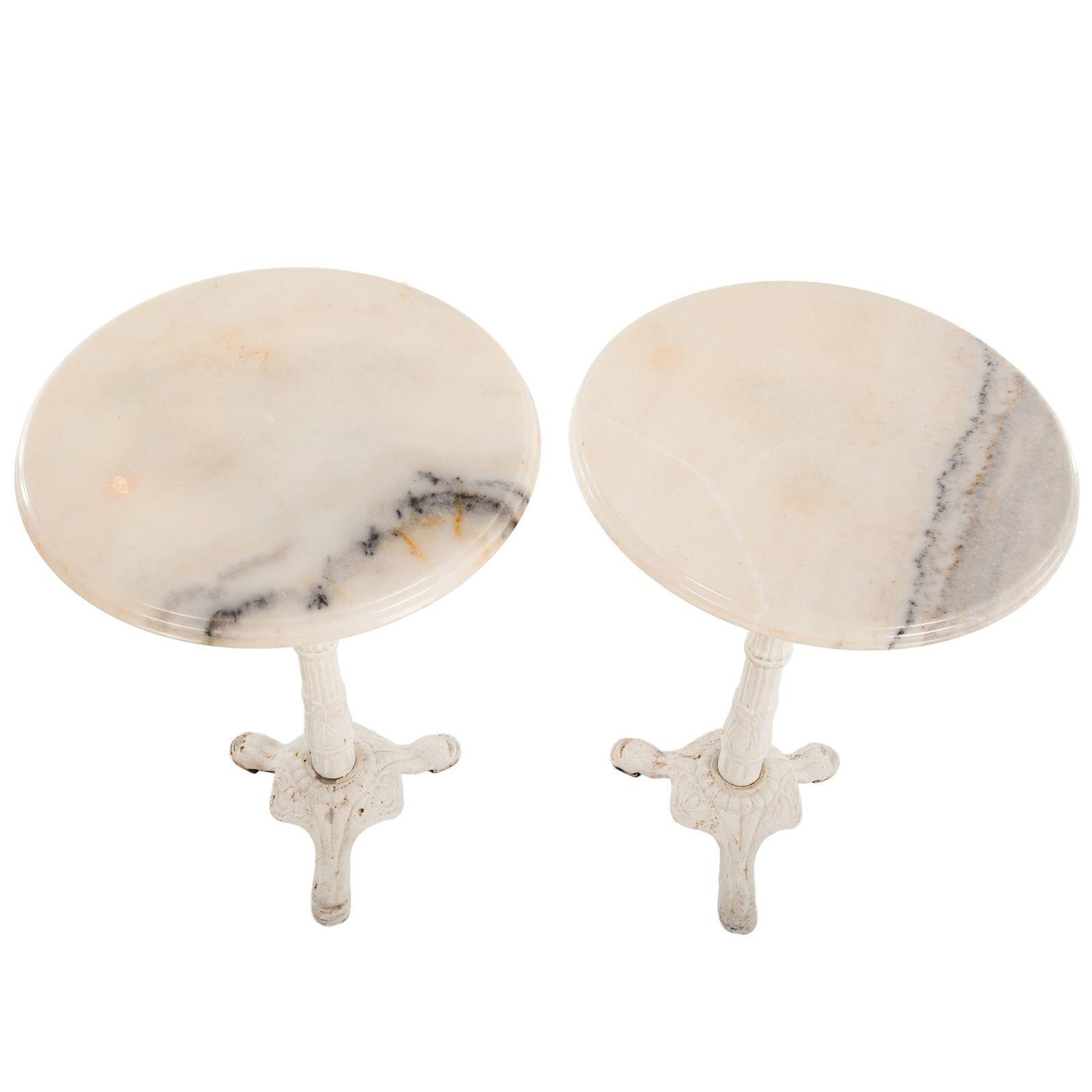 A Pair of Marble & Cast Iron Pedestal End Tables. Variegated black and white marble tops on painted classical style cast iron pedestal bases. Beautiful indoor/outdoor marble bistro/side tables with painted cast iron base and white marble top.