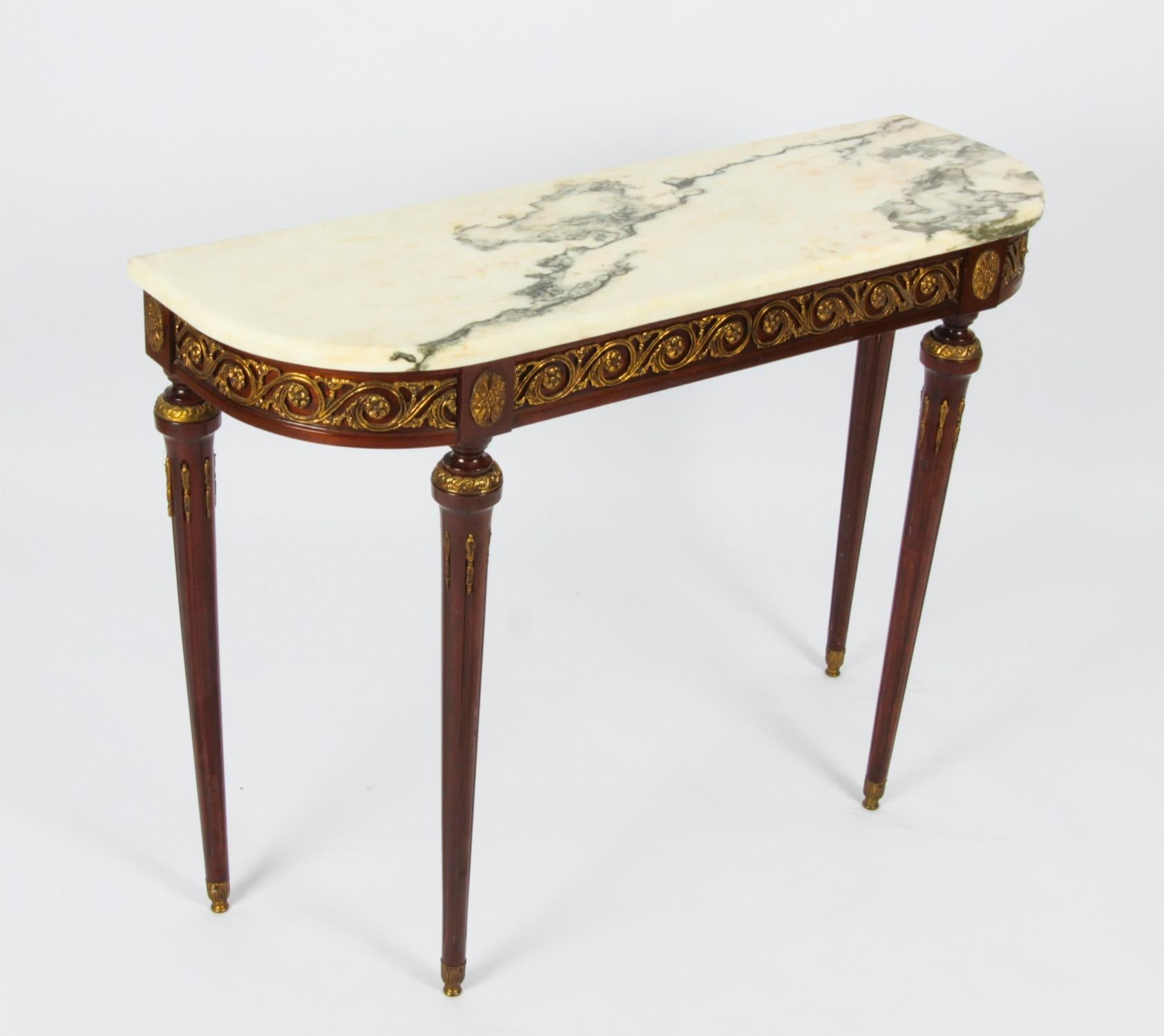 This is a beautiful vintage pair of Meuble Francais Louis Revival console tables, mid 20th century in date.
 
They have been accomplished in mahogany with beautiful demi-lune shaped white marbles top above fantastic ormolu mounted floral decoration