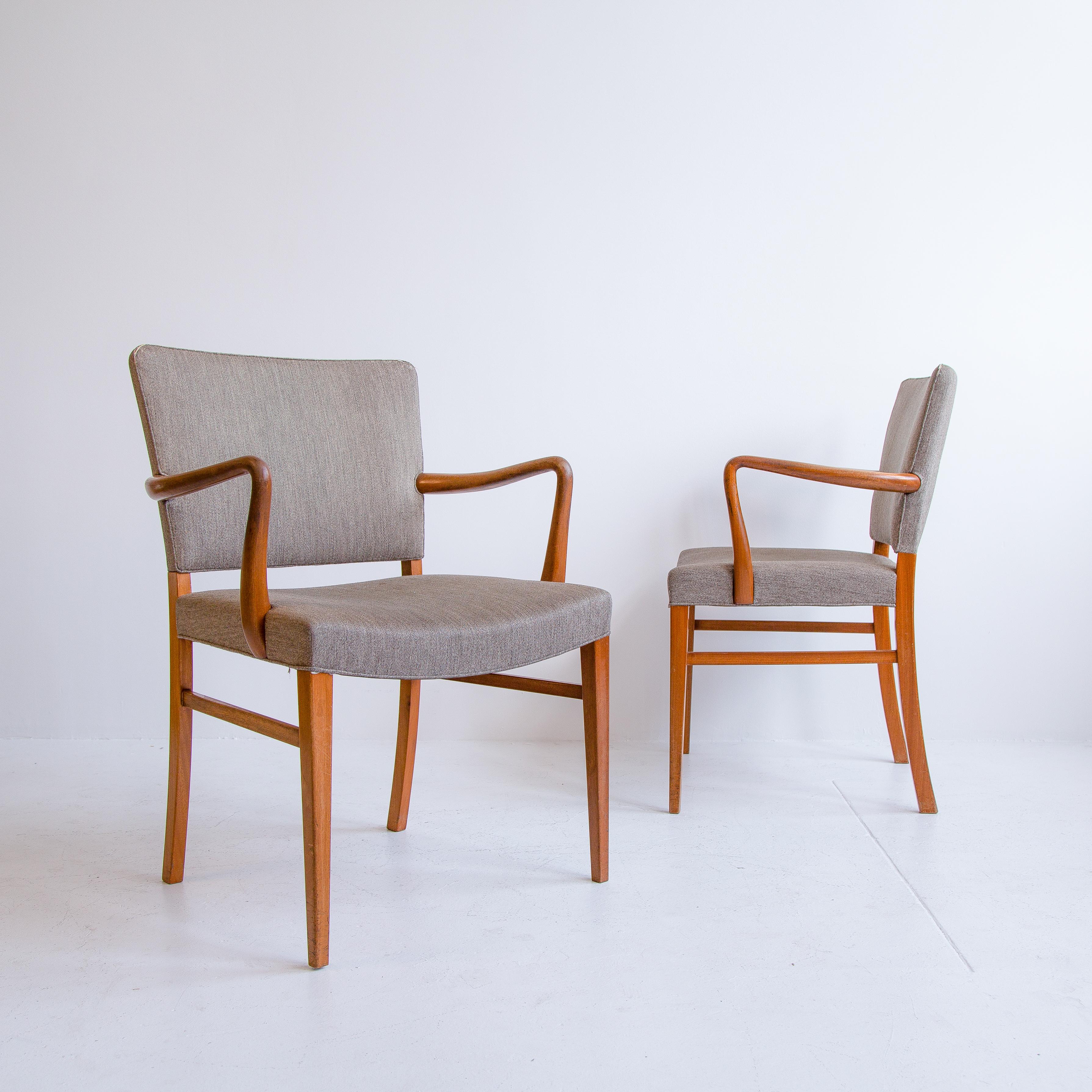 A matching pair of vintage Ole Wanscher designed armchairs manufactured by A.J. Iversen in Denmark in the 1950s. These chairs feature a solid beech wood frame with flowing curved arms and back legs. The wood frame has developed a beautiful vintage