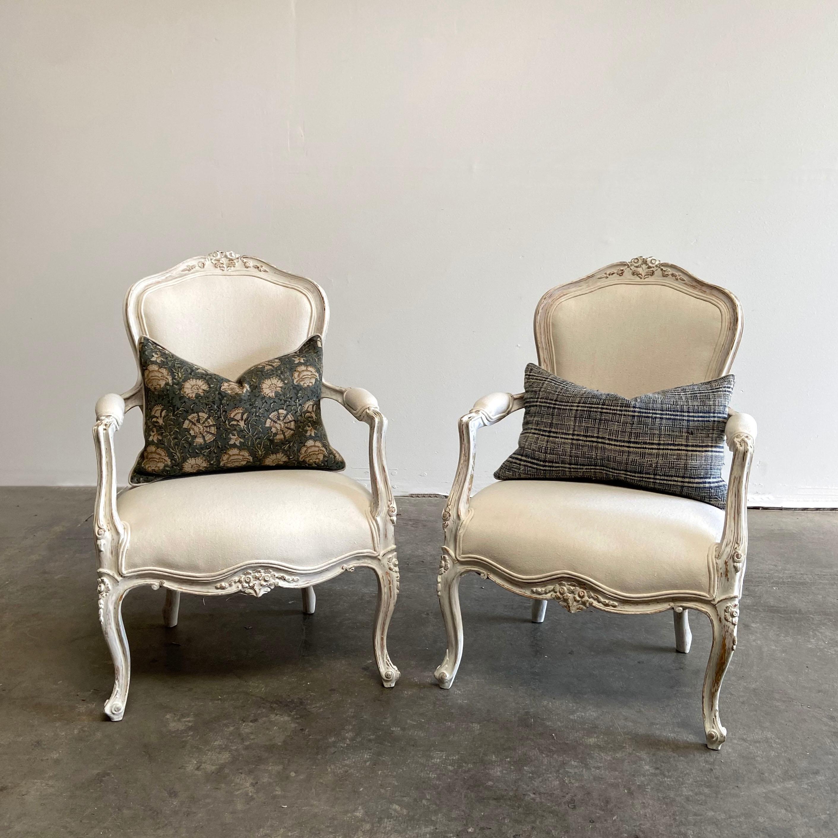 Vintage pair of painted and upholstered Louis XV style open armchairs
Beautiful painted chairs in soft white with subtle antique distressing. An oyster grey hue, with gilt flecks peeking through the paint. Soft rounded scrolls, and hand carved