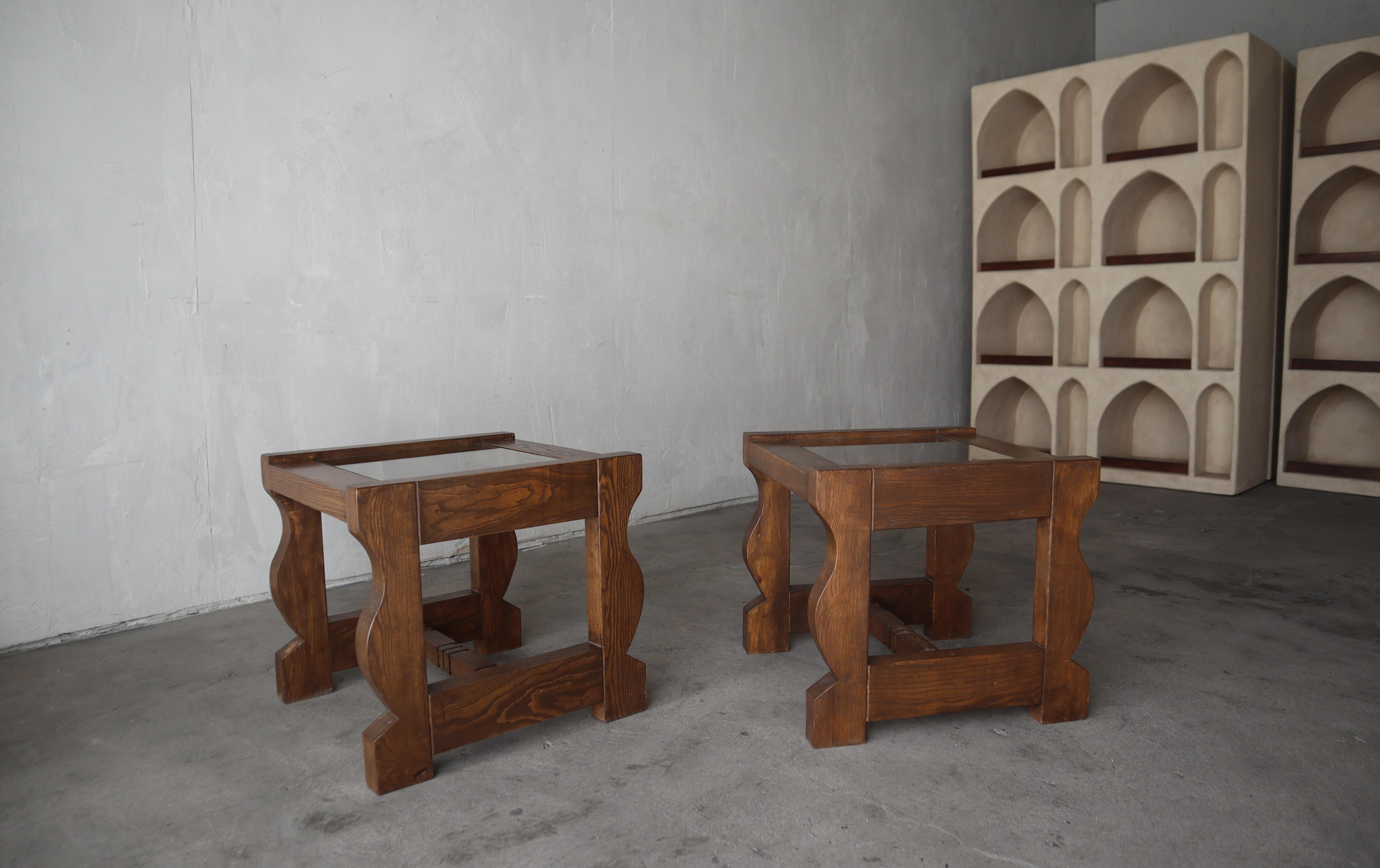 Bellissima coppia di tavolini artigianali in pino scuro con piano in vetro. Adoro i dettagli sinuosi di queste scarpe.

I tavoli sono strutturalmente solidi e in ottime condizioni generali. Presentano un'usura minima dovuta all'età e all'uso,