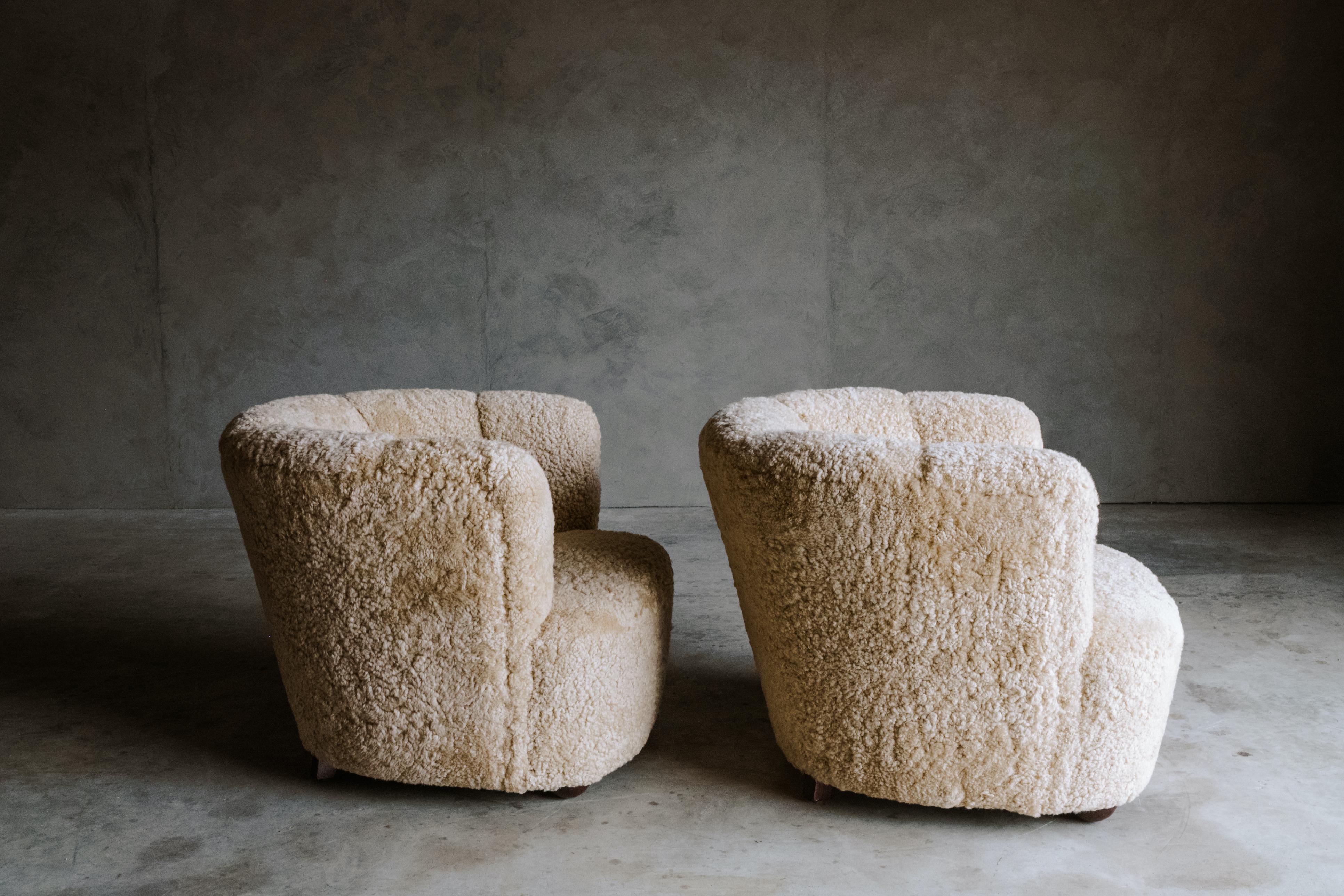 Vintage pair of sheepskin lounge chairs from Denmark, Circa 1950. Nice barrel back shape. Professionally reupholstered in Denmark with very soft light tan shearling.