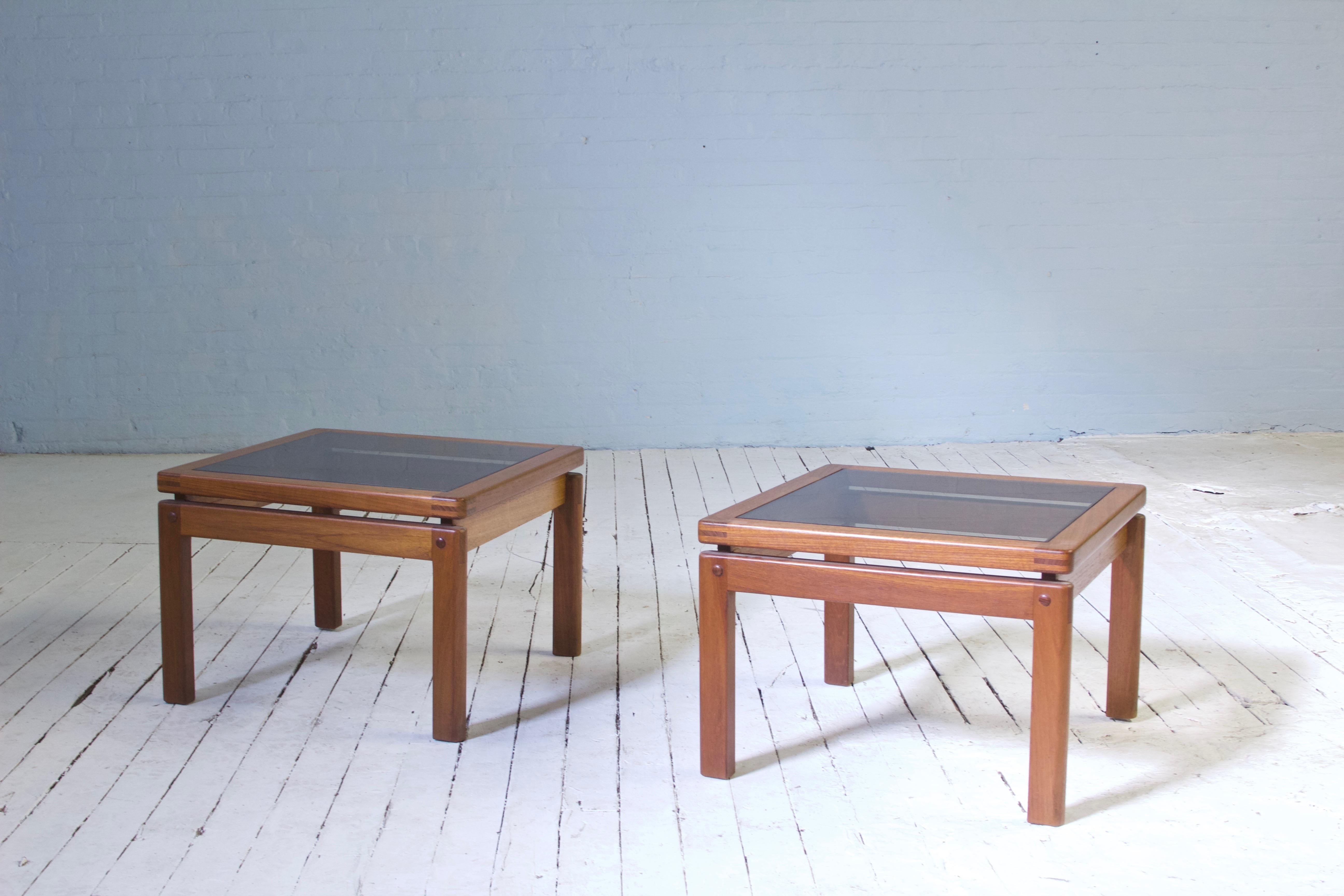 Lovely pair of side tables with exposed finger joinery featuring solid teak frames and tinted glass tops. This design highlights an exciting interplay between straight lines and curves--a simple rectilinear frame is elevated by carefully chosen