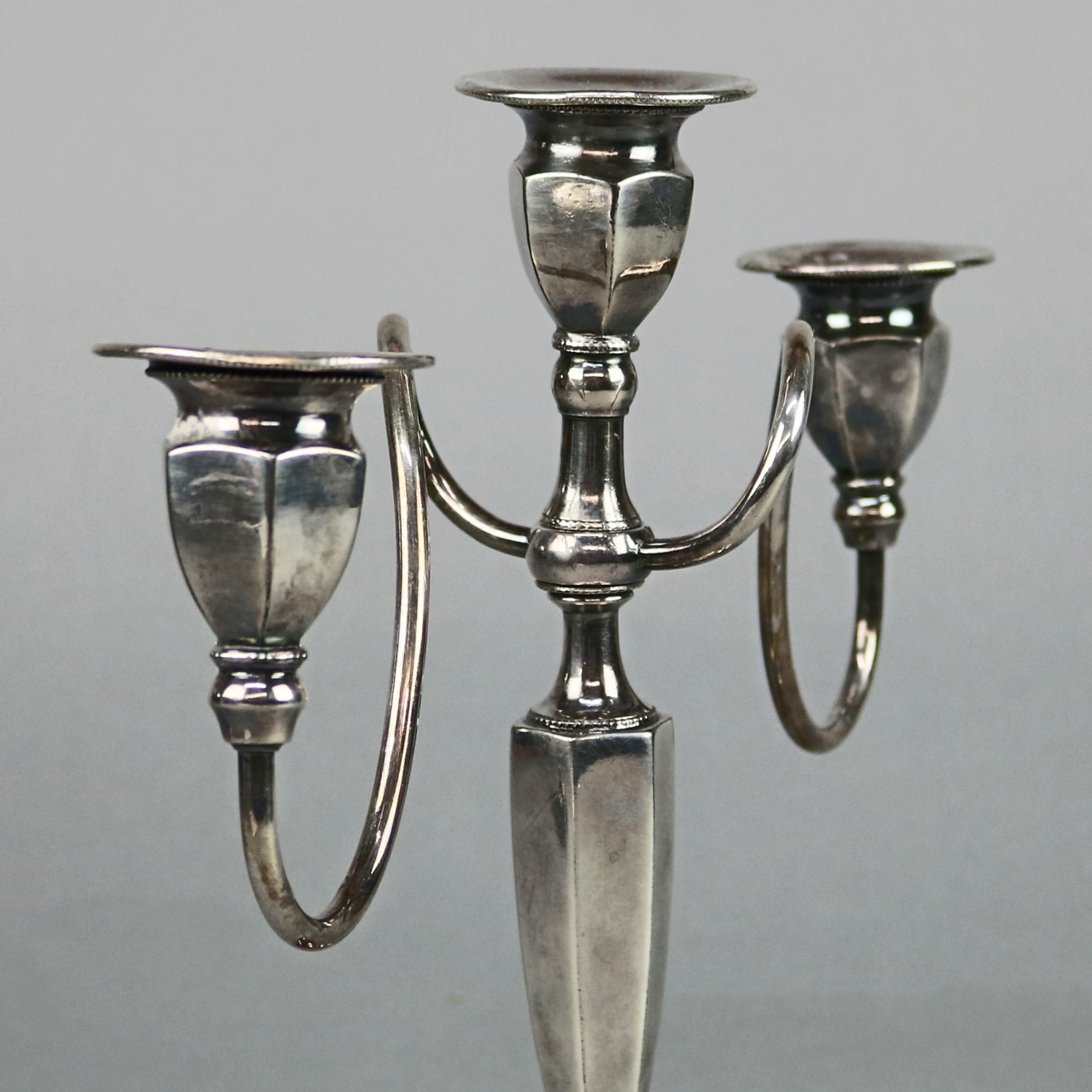 A vintage pair of candelabra each offers central candle socket flanked by scroll form arms terminating in candle sockets surmounting faceted stylized urn form column seated on stepped base, stamped as photographed, circa 1930

Measures: 10.25