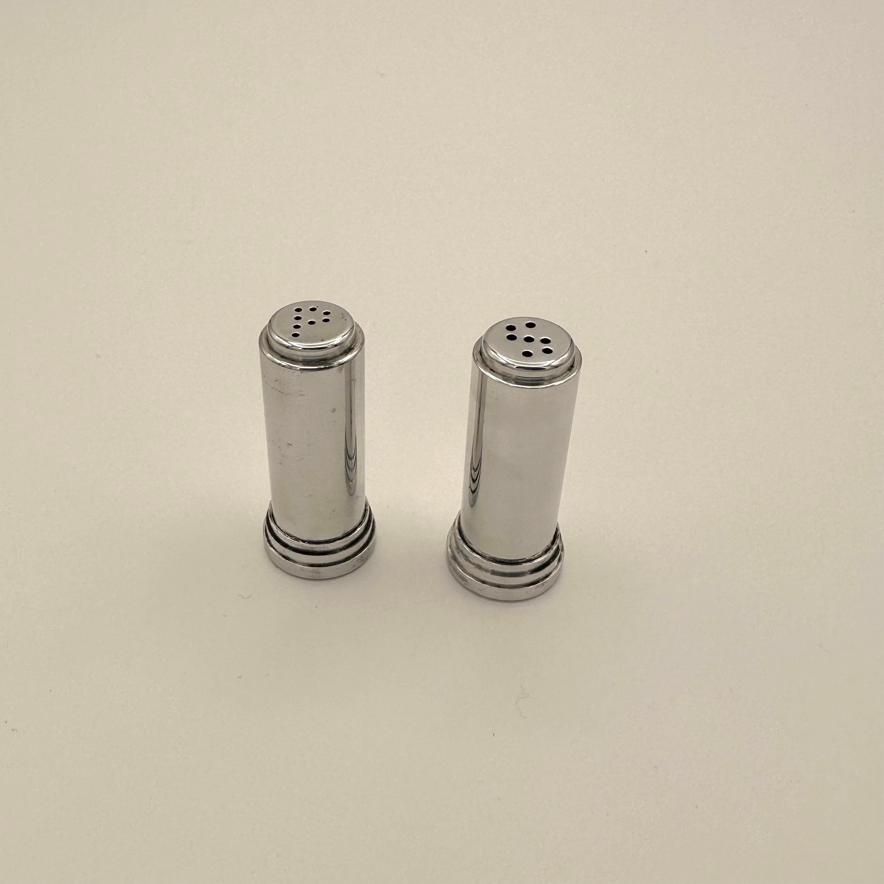 Small pair of vintage salt and pepper shakers with an Art Deco, Modernist, Machine Age style. Circular layered stepped base and round column form with a final stepped notch at the top. Salt and pepper are shaken through stylized holes on the top
