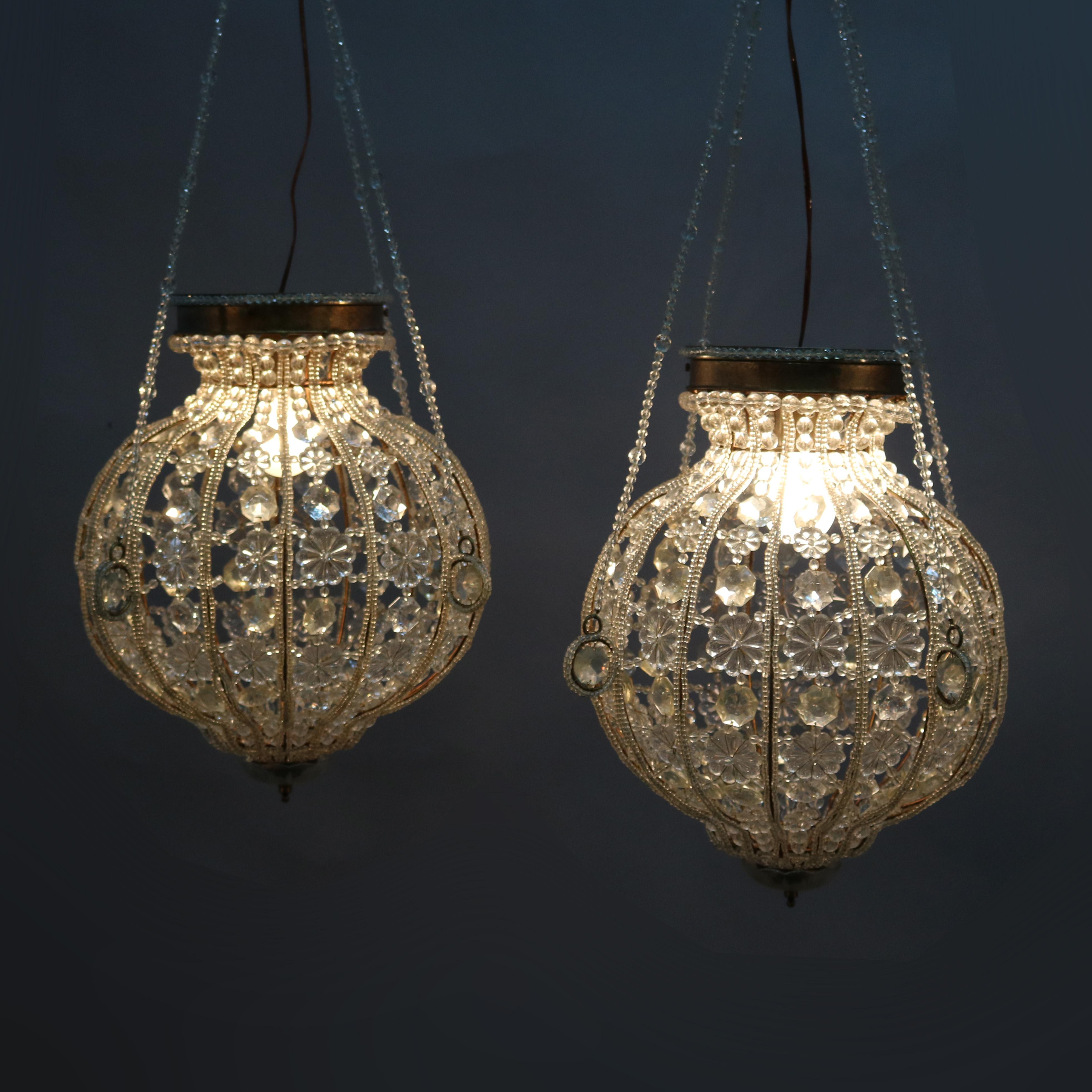 A pair of vintage chandeliers offer brass frames with cut beaded, faceted and floral form crystals in spherical form with strung crystal garland, 20th century

Measures: 36
