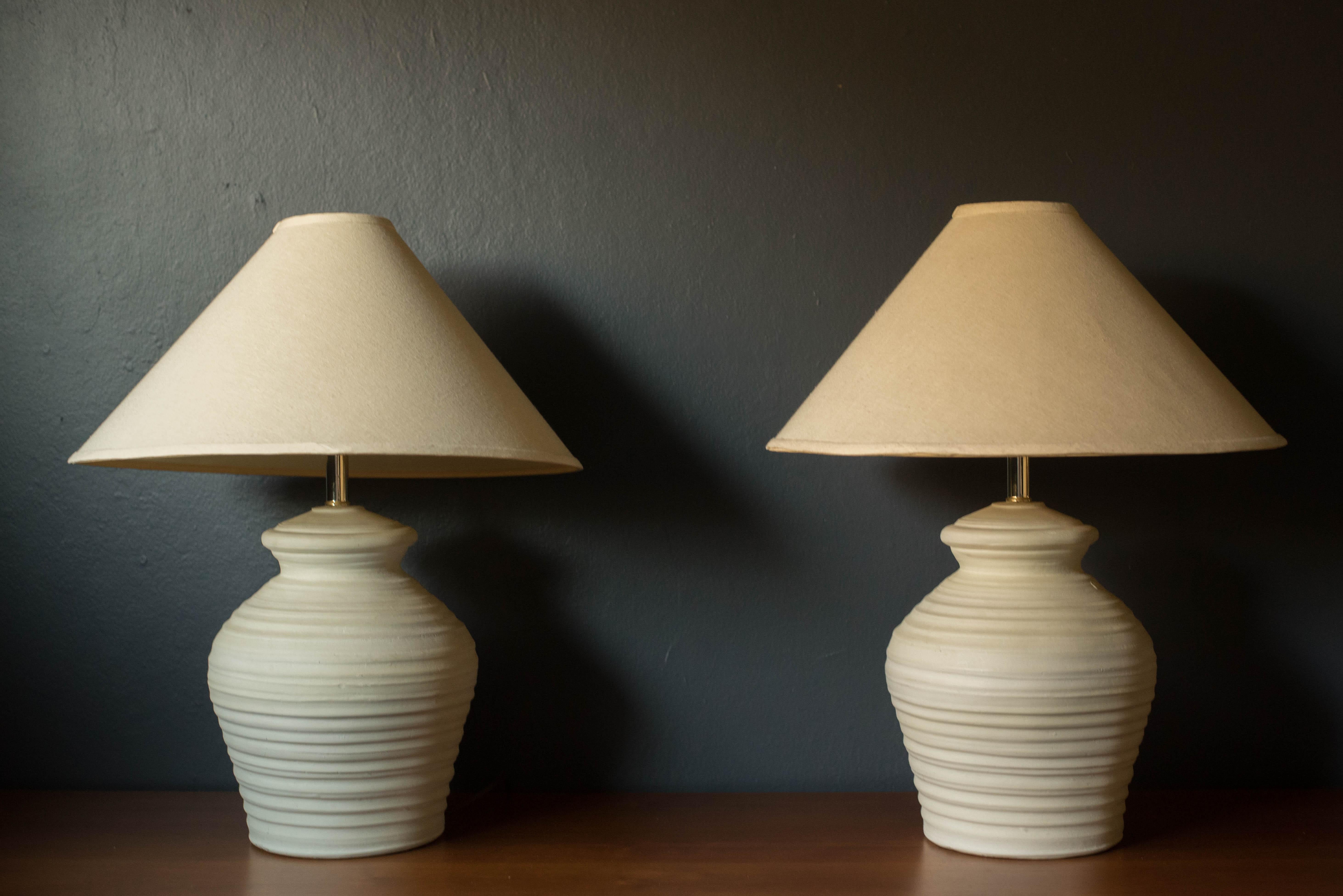 Pareja de lámparas de sobremesa de cerámica escultórica vintage de hacia 1980. Este conjunto clásico presenta un acabado mate texturizado en un tono marfil natural hueso. Equipado con un mecanismo de conmutación de tres vías y marcado Elite '88.