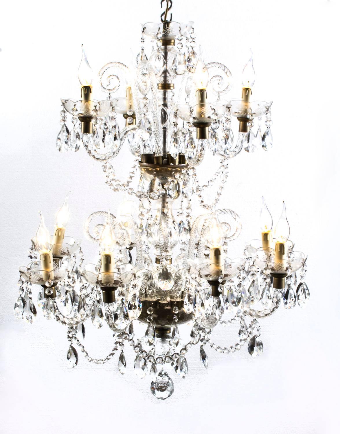 This is a stunning pair of vintage Venetian style two-tier crystal chandelier with twelve lights each and beautiful clear crystal drops, dating from the second half of the 20th century.

There are four lights on each top tier and eight on each