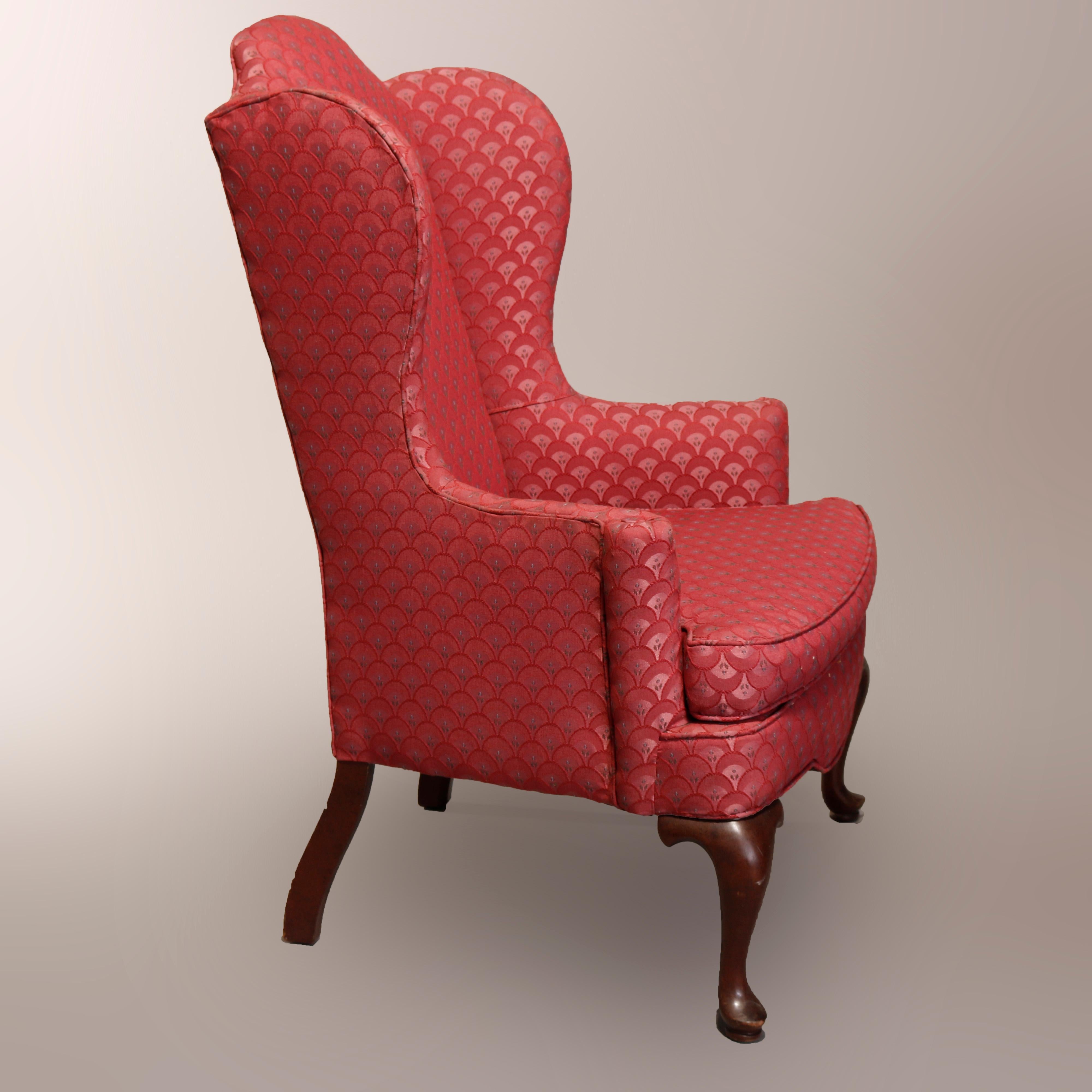 A vintage pair of Queen Anne style upholstered fireside chairs offer shaped crest over wing back and scroll form arms, raised on mahogany cabriole legs terminating in pad feet, 20th century

Measures: 45.5