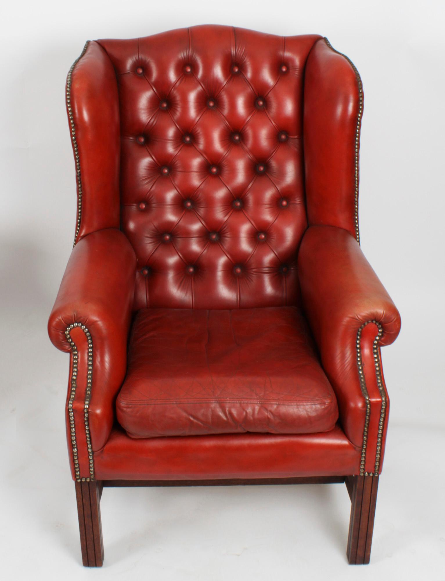 This is an excellent vintage pair of English handmade red leather button backed wingback armchairs, dating from the late 20th century.

They have deep buttoned backs, swept shaped sides and loose cushion seats, and they are raised on square