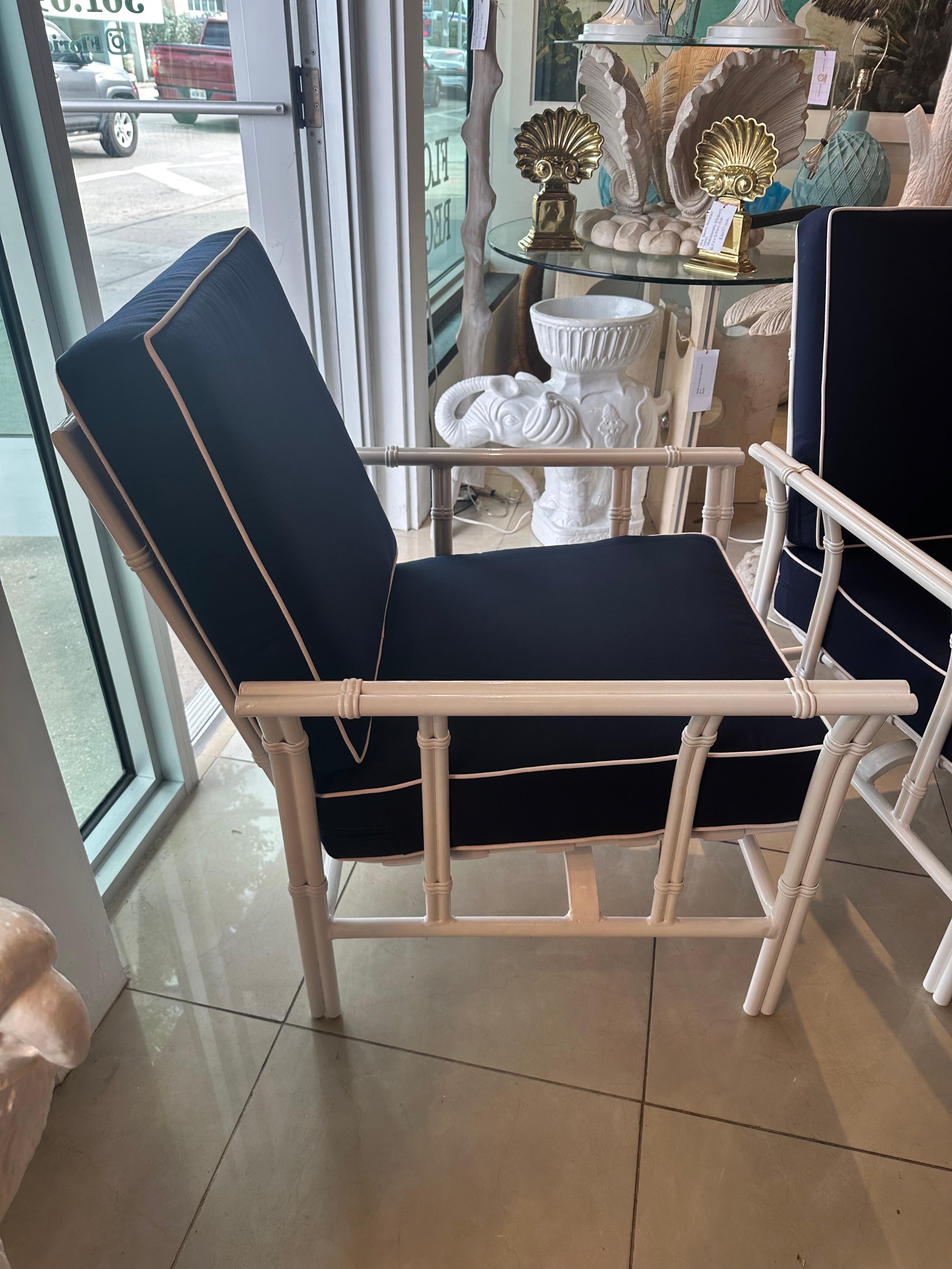 Vintage 1970s 3 piece patio, porch, outdoor set which includes pair of rocking chairs and ottoman, footstool. Faux Bamboo. Newly powder-coated in a crisp white. All new foam cushions and Sunbrella navy blue and white upholstery. These are super